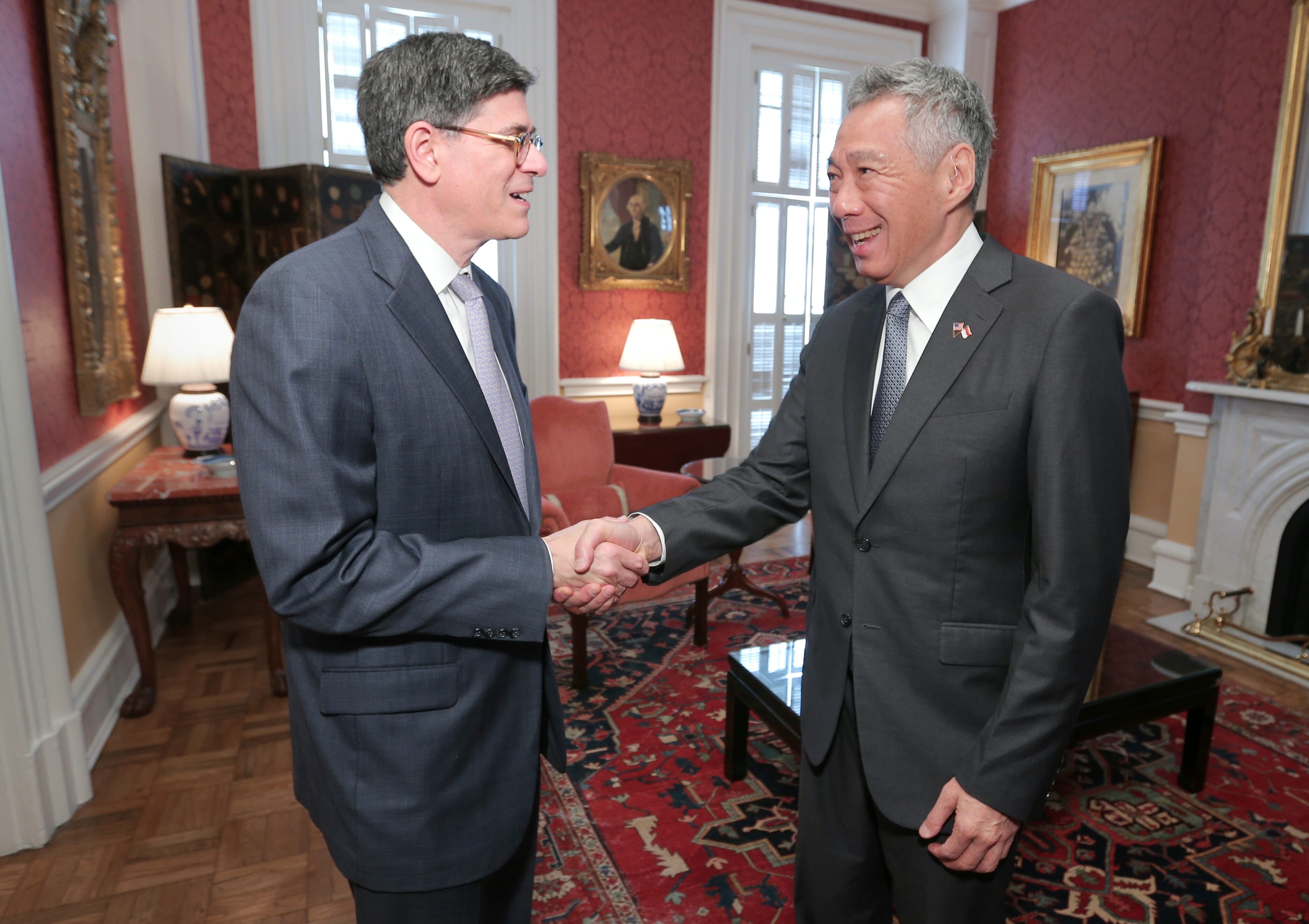 Two men in suits shaking hands indoors, Lee Hsien Loong visible on right.