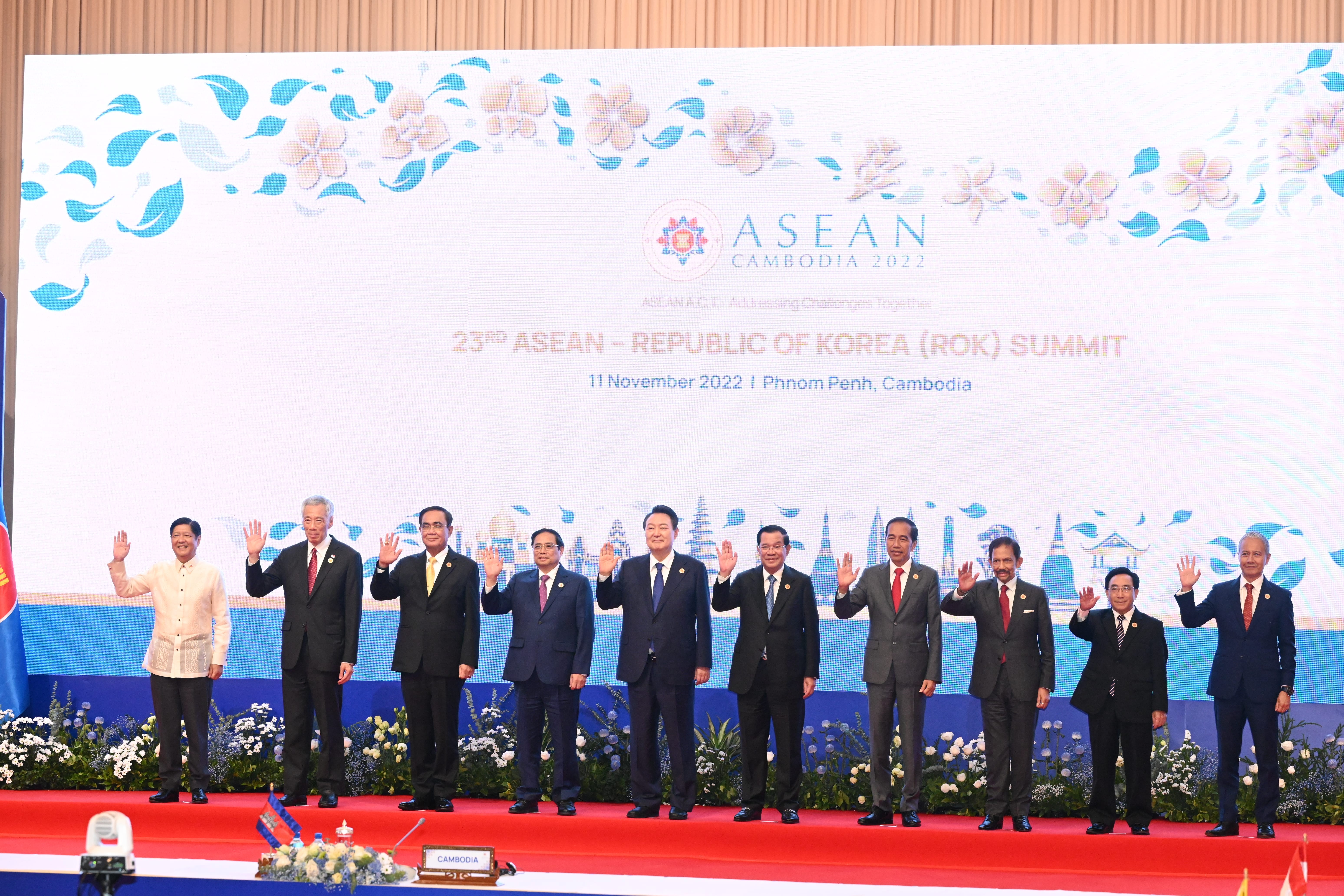Leaders in suits wave at 23rd ASEAN-ROK Summit with "ASEAN Cambodia 2022" backdrop.