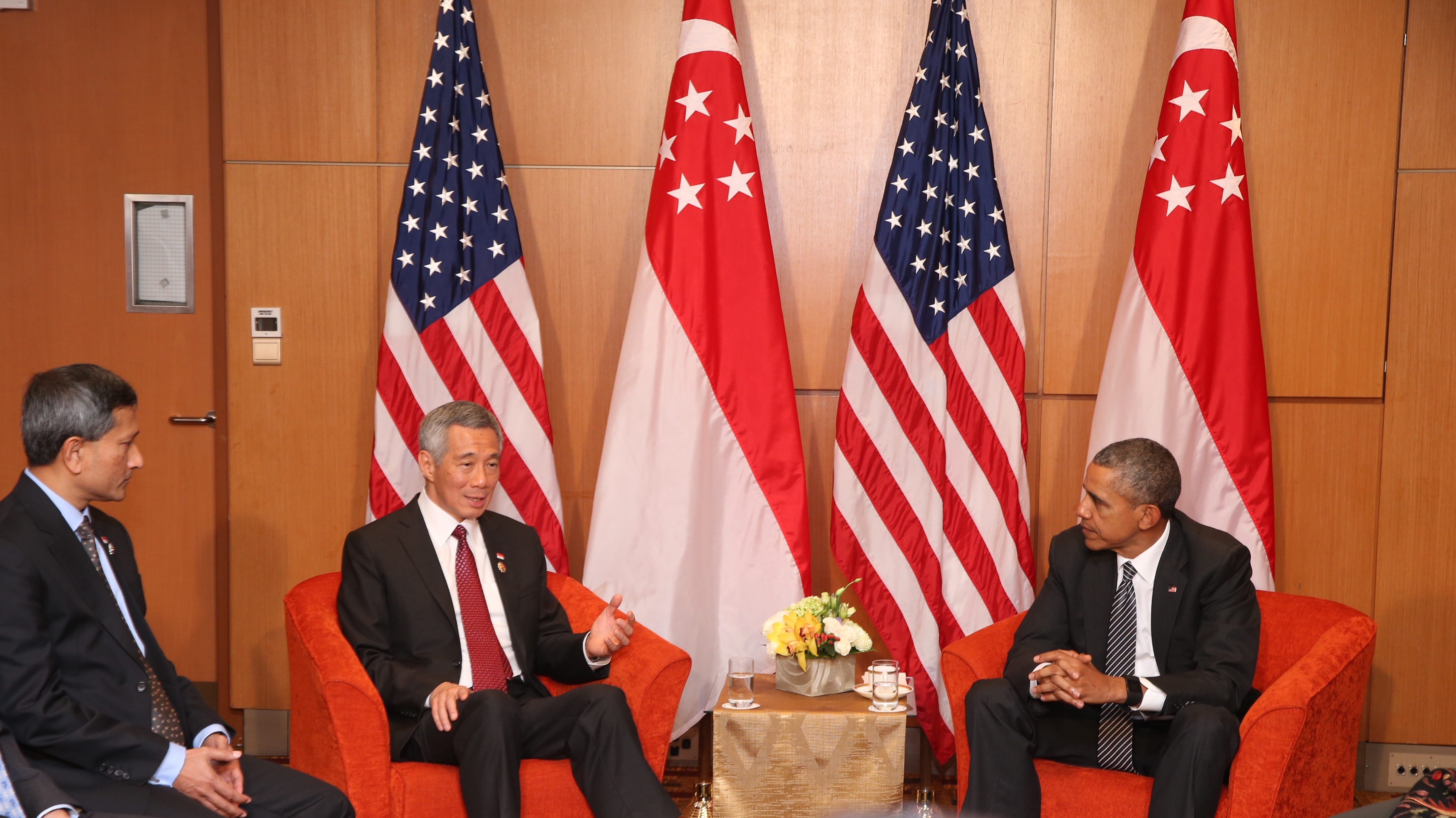 Lee Hsien Loong and Barack Obama sit in armchairs before US and Singapore flags.