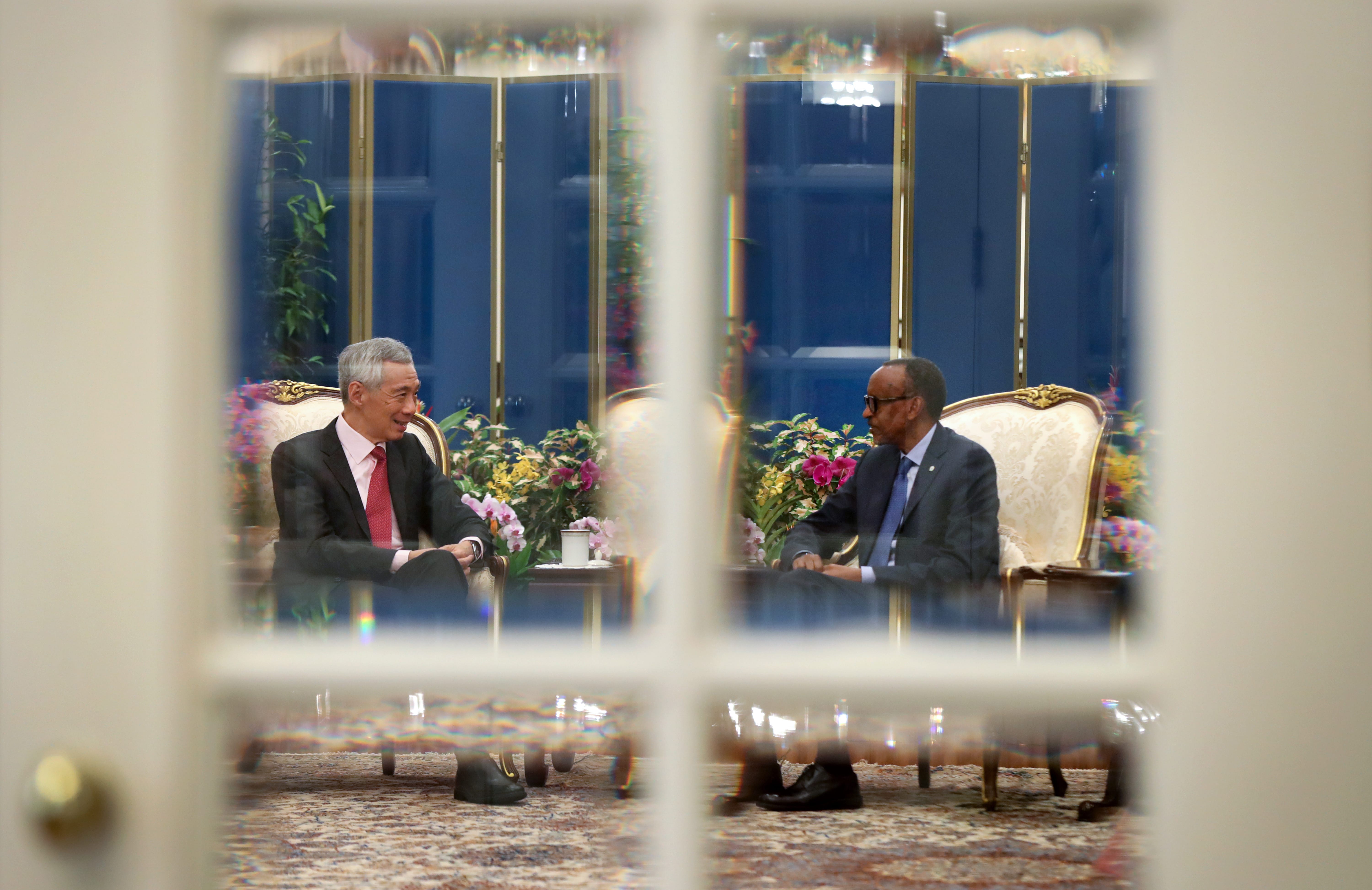 Through white double doors: Lee Hsien Loong and Paul Kagame sit in ornate chairs across from each other.