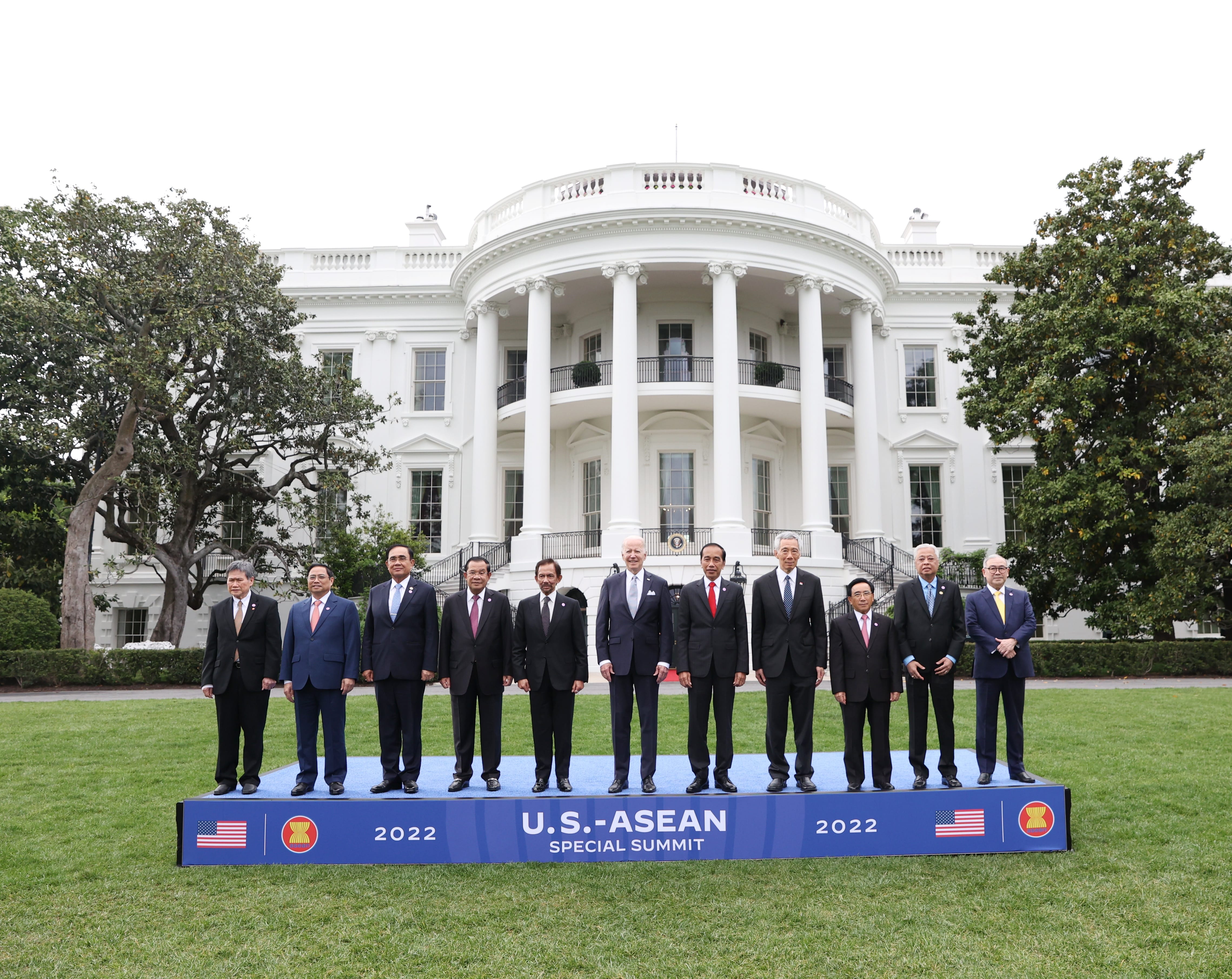 Group of people including Joe Biden on a platform in front of the White House.