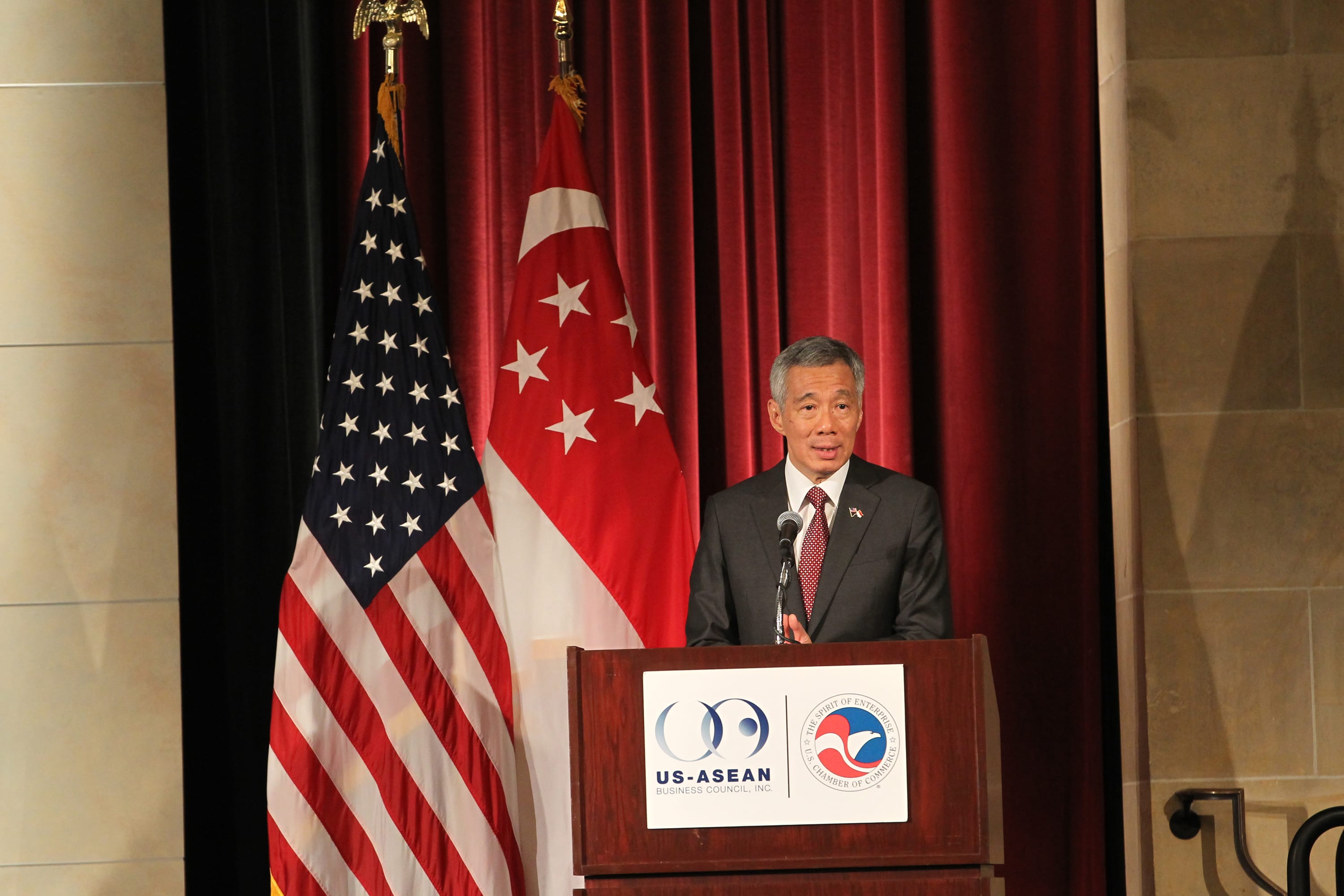 Lee Hsien Loong at a podium with US and Singapore flags.