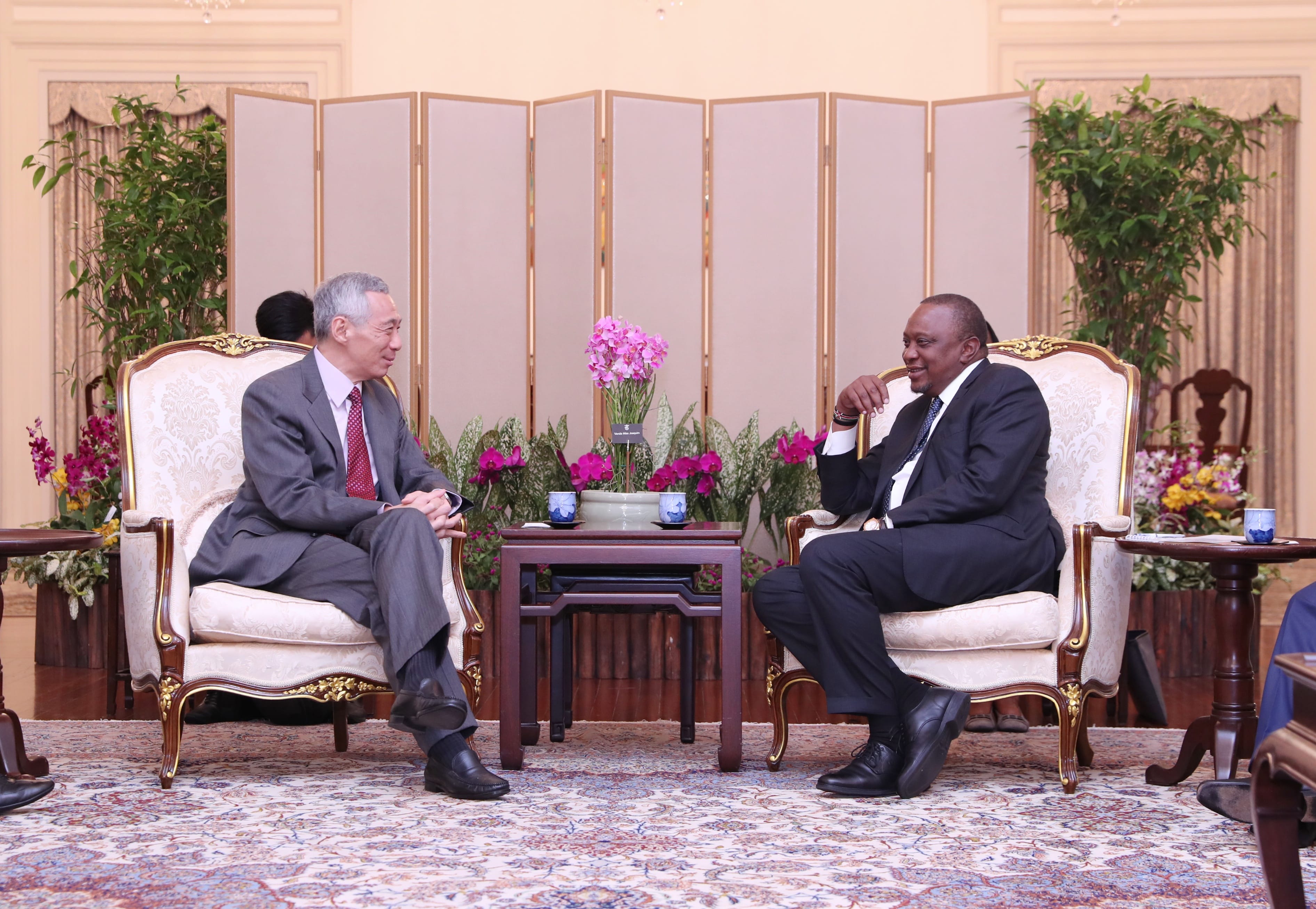 Lee Hsien Loong and William Ruto sit in ornate chairs with table of flowers between them.