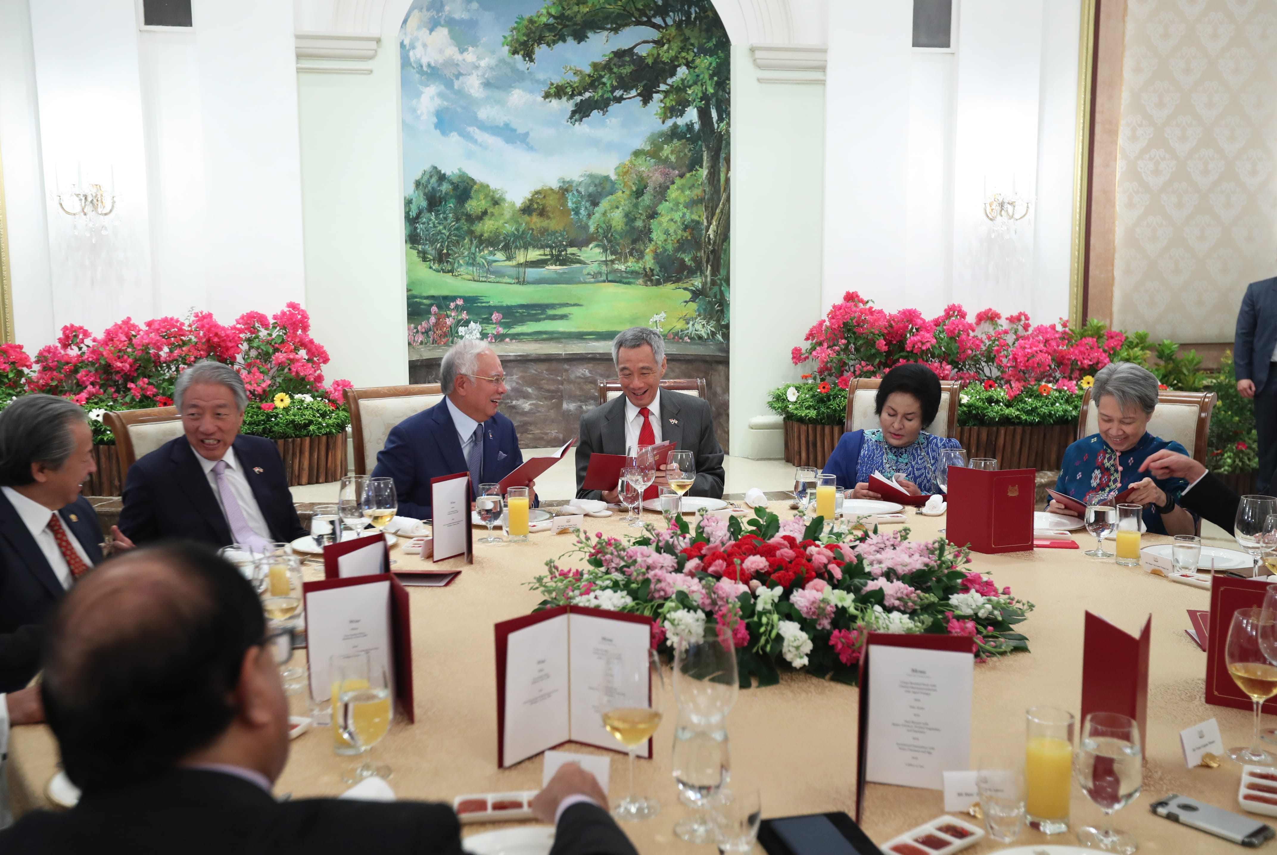 Dignitaries seated at a flower-adorned table with menus and glassware. Lee Hsien Loong visible.