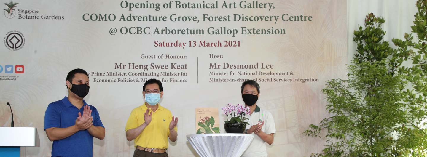 Three masked men at Singapore Botanic Gardens event, applauding near plants and signage.