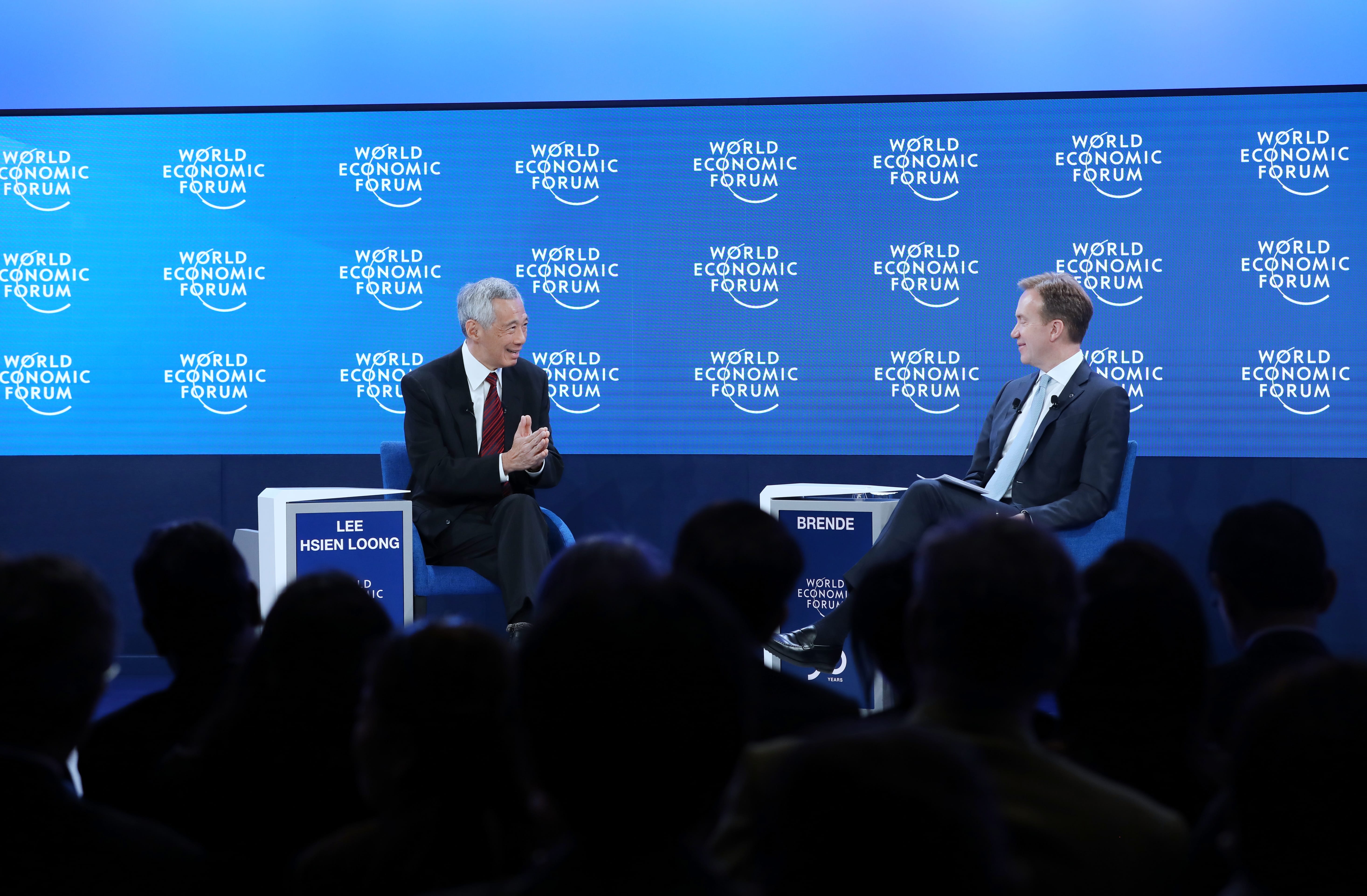 Lee Hsien Loong and Brende seated, speaking on stage at World Economic Forum event, audience visible.
