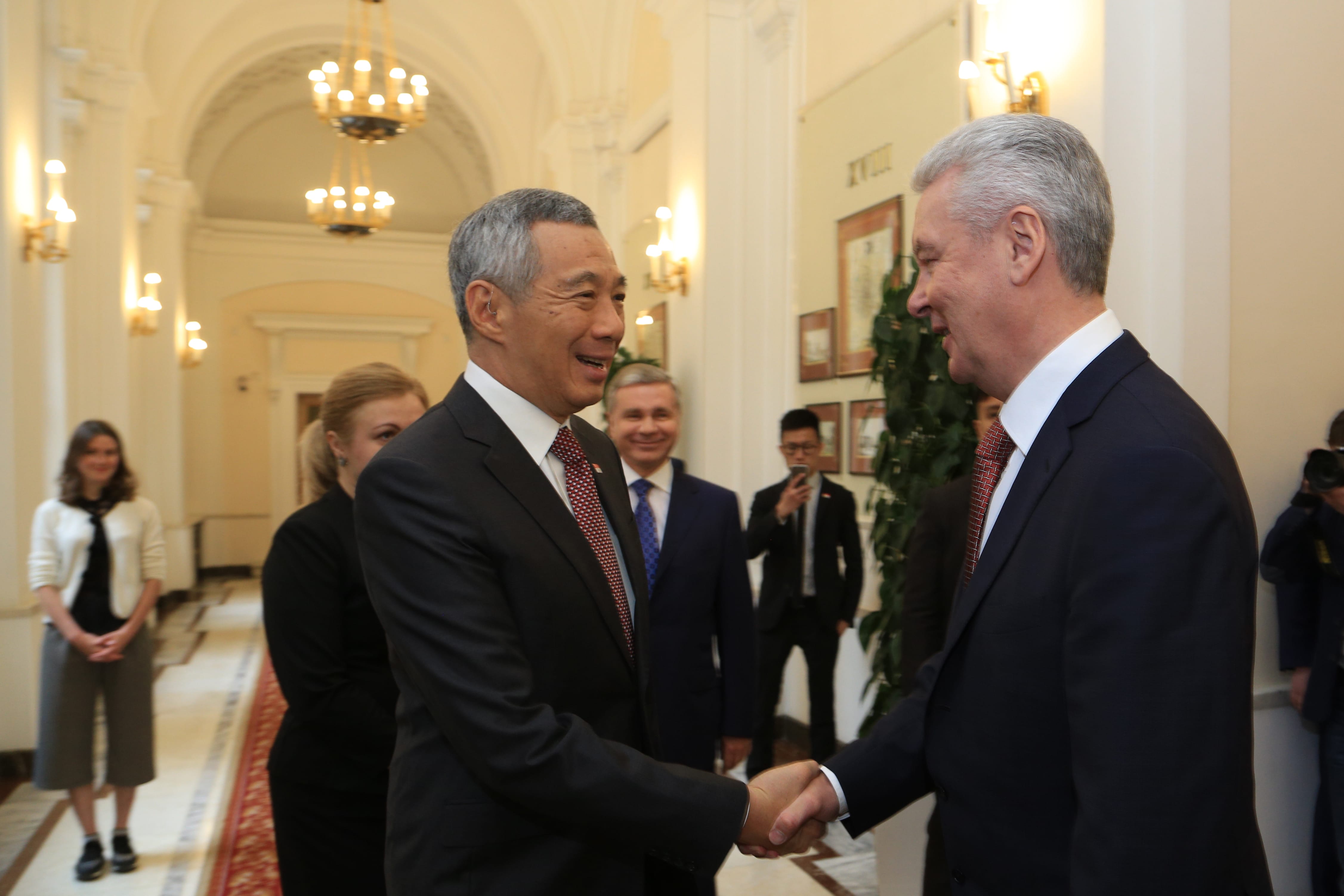 Lee Hsien Loong shakes hands with Sergei Sobyanin in a formal hall.