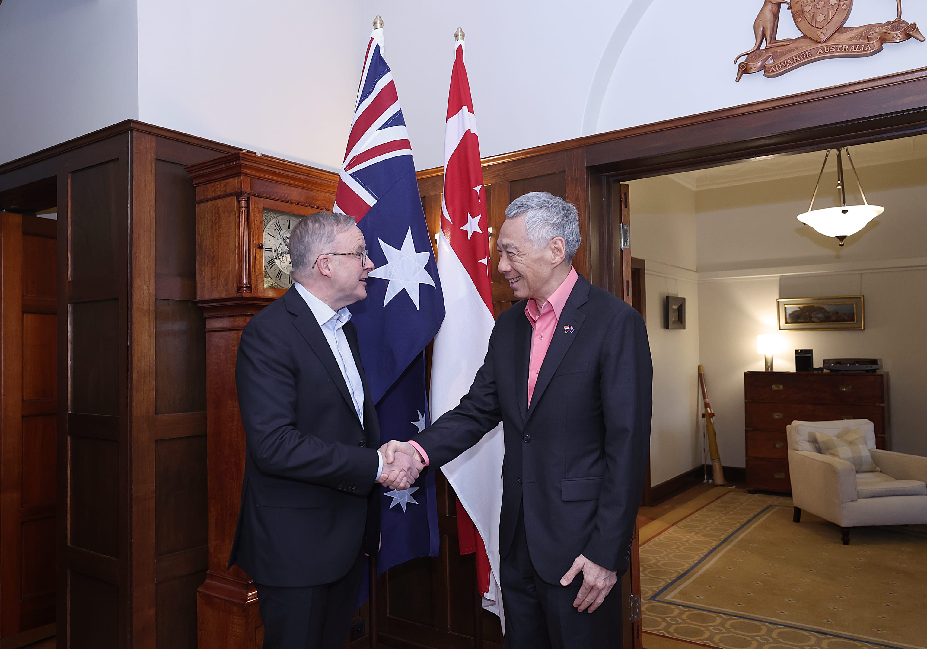 Anthony Albanese and Lee Hsien Loong shake hands before Australian & Singapore flags.