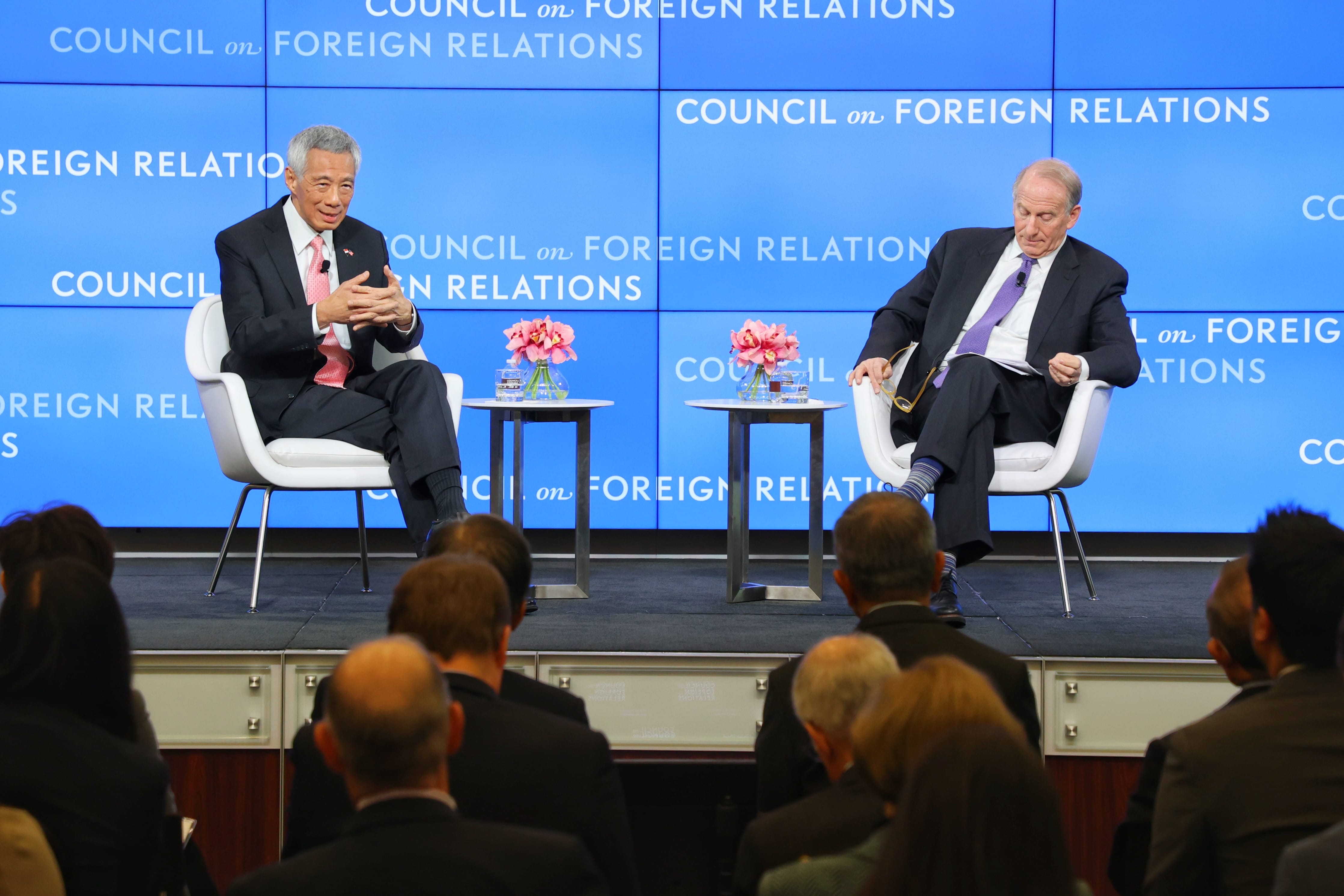 Two men in suits on stage at a "Council on Foreign Relations" event before an audience.