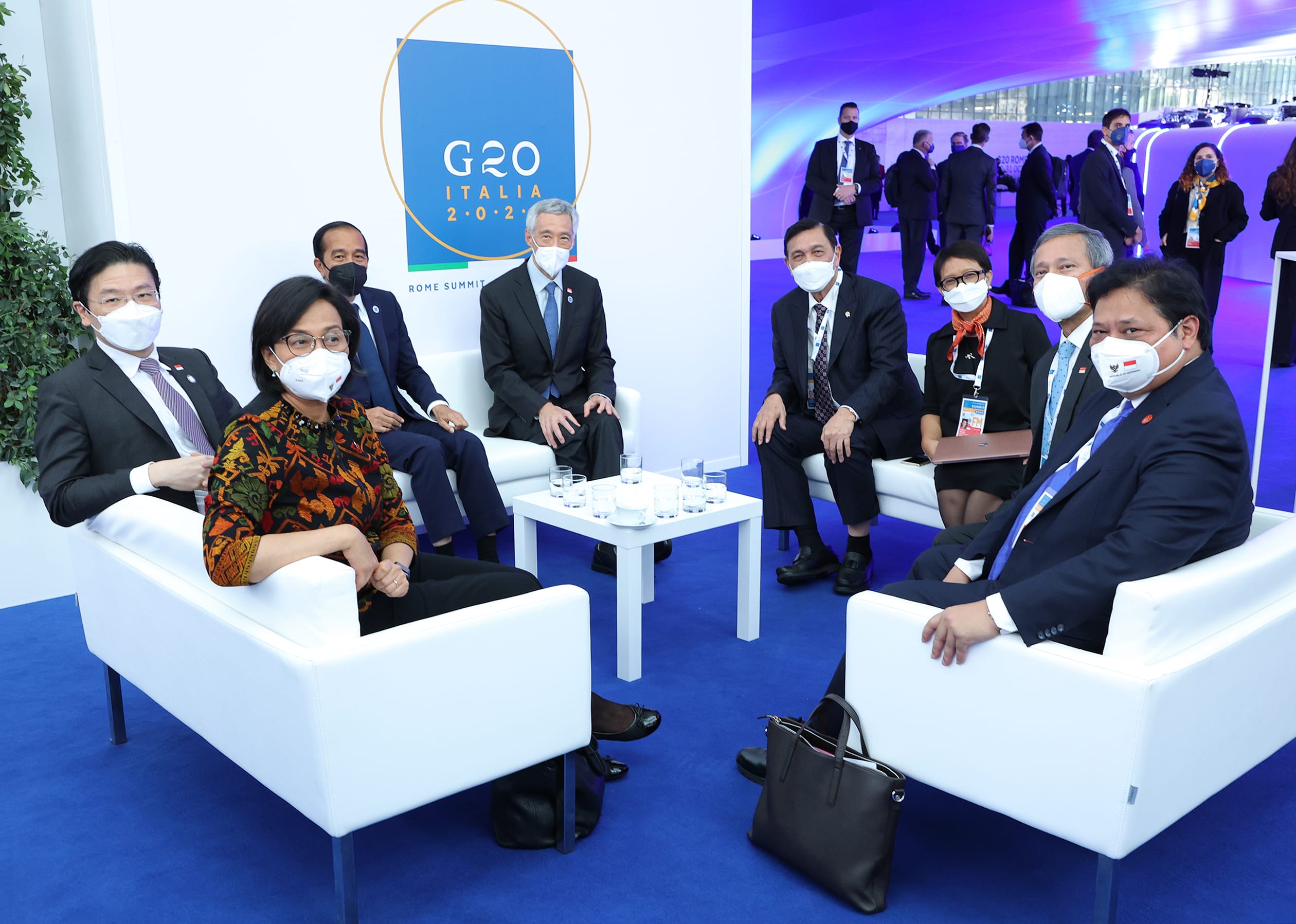 Group of masked dignitaries seated at G20 Italia conference, white chairs, blue carpet.