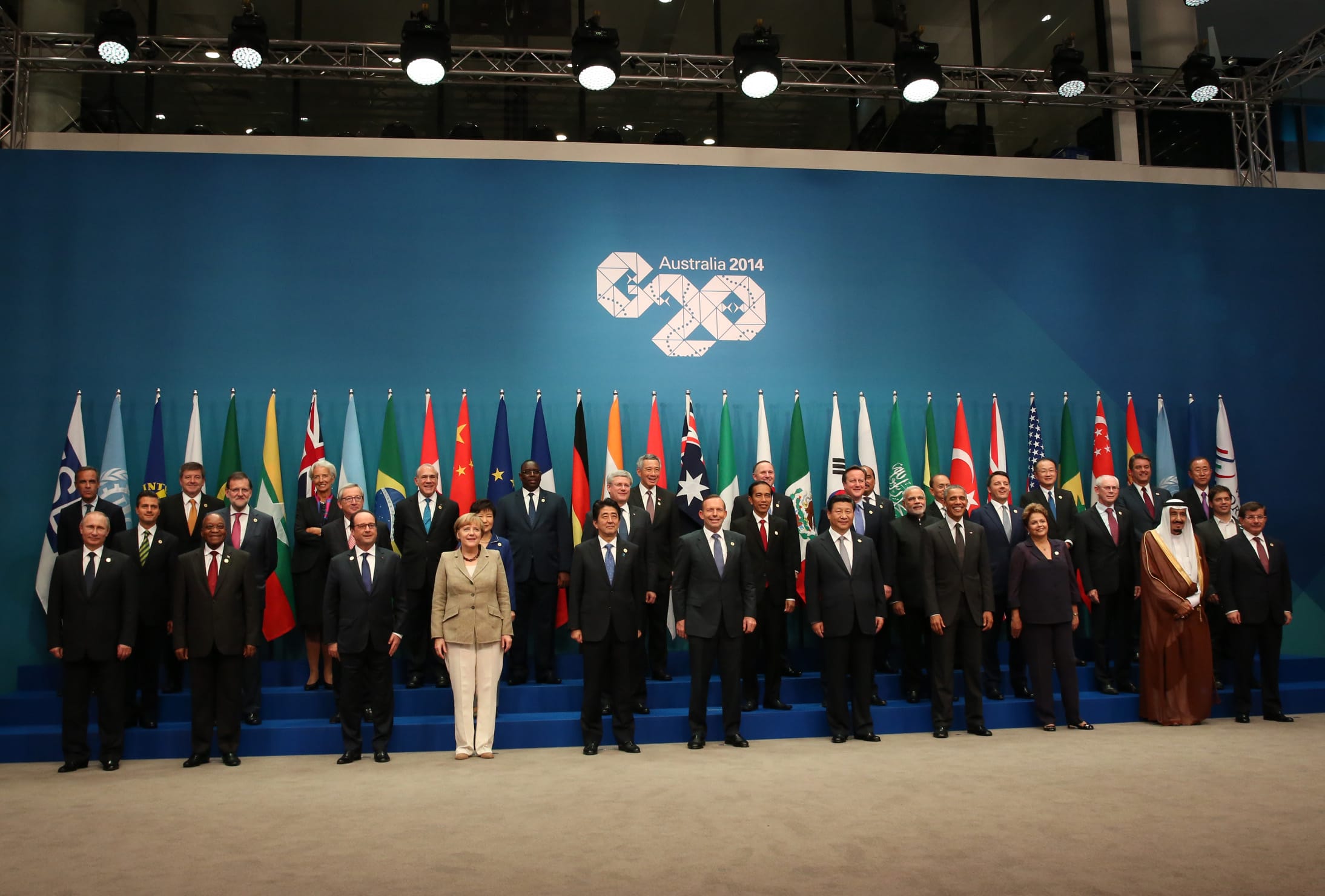 Group photo of world leaders at the Australia 2014 G20 summit, standing before national flags.