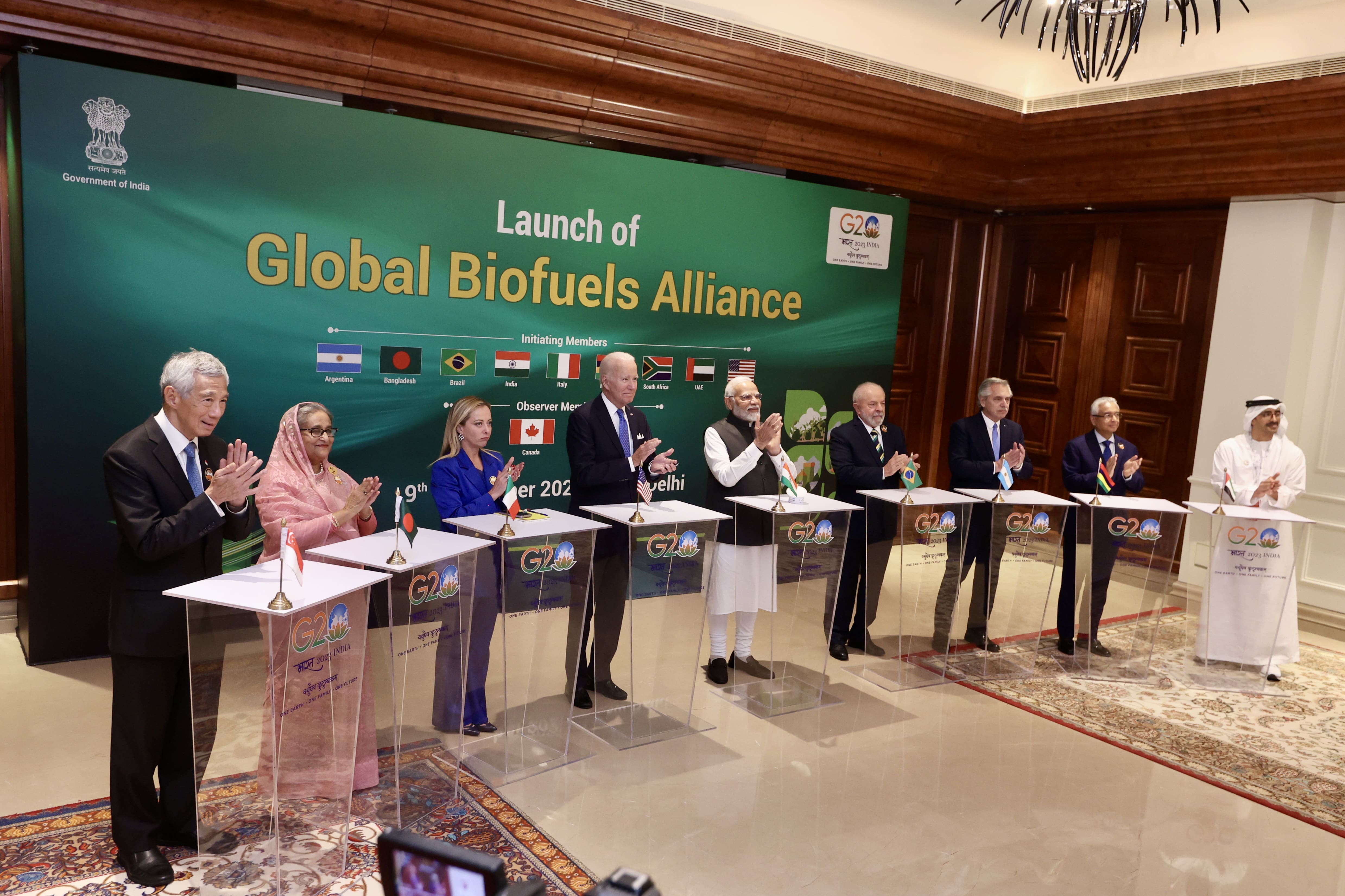 World leaders, including Biden and Modi, at the 'Global Biofuels Alliance' launch, applauding. G20 logo visible.