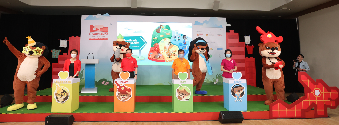 Heartlands Festival event with people, mascots, and colored boxes labeled Celebrate, Play, Eat, Shop.