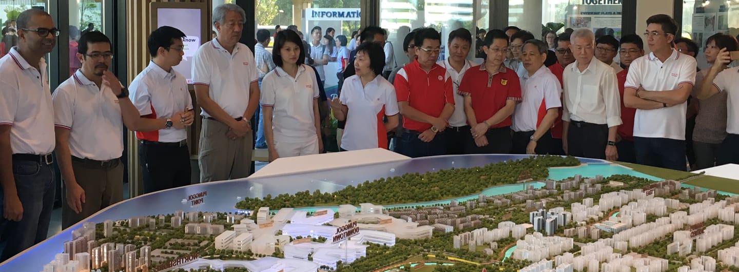 A group of people look at a detailed architectural model of a cityscape.