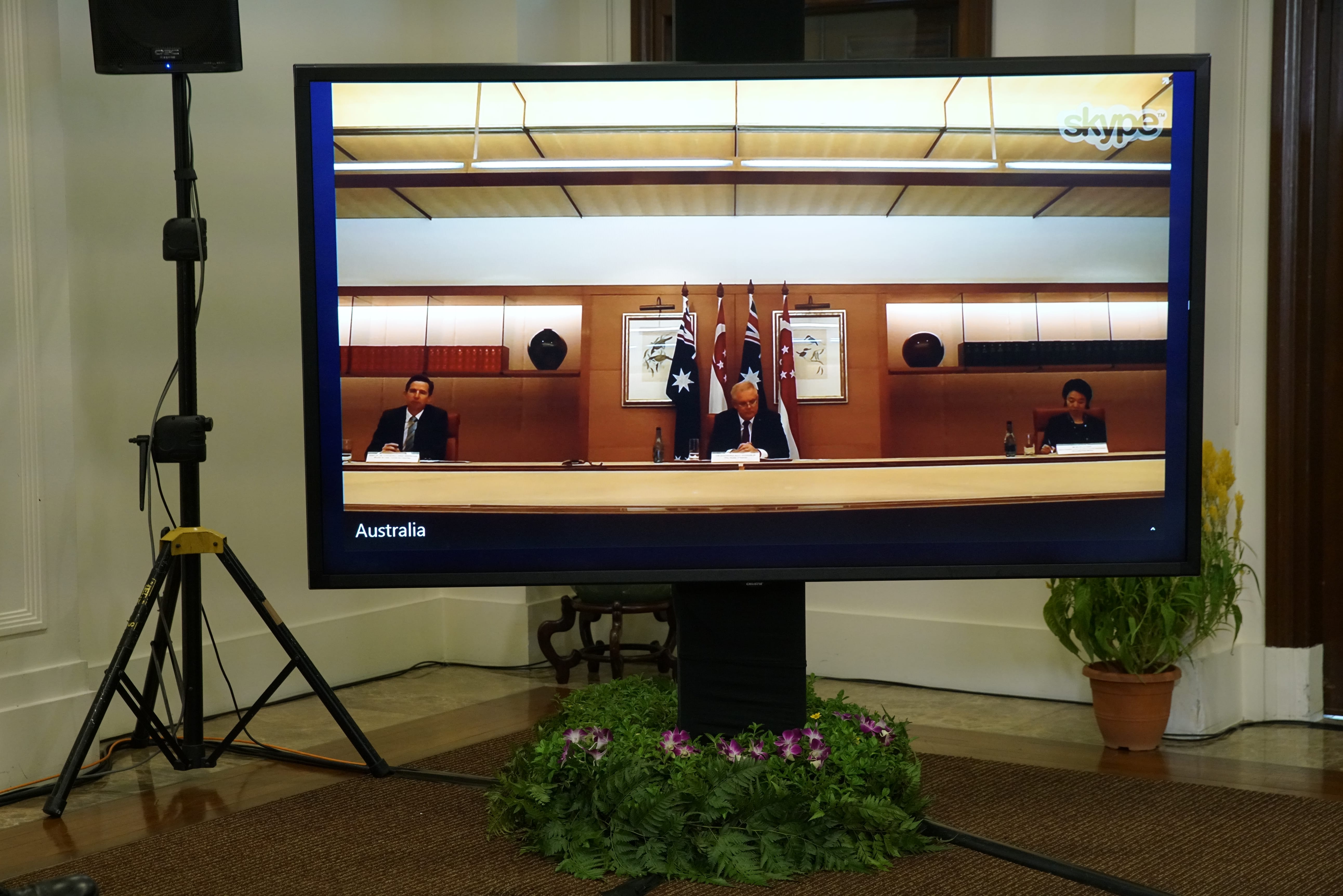 Large monitor displaying a Skype call from Australia with three people and Australian flags.