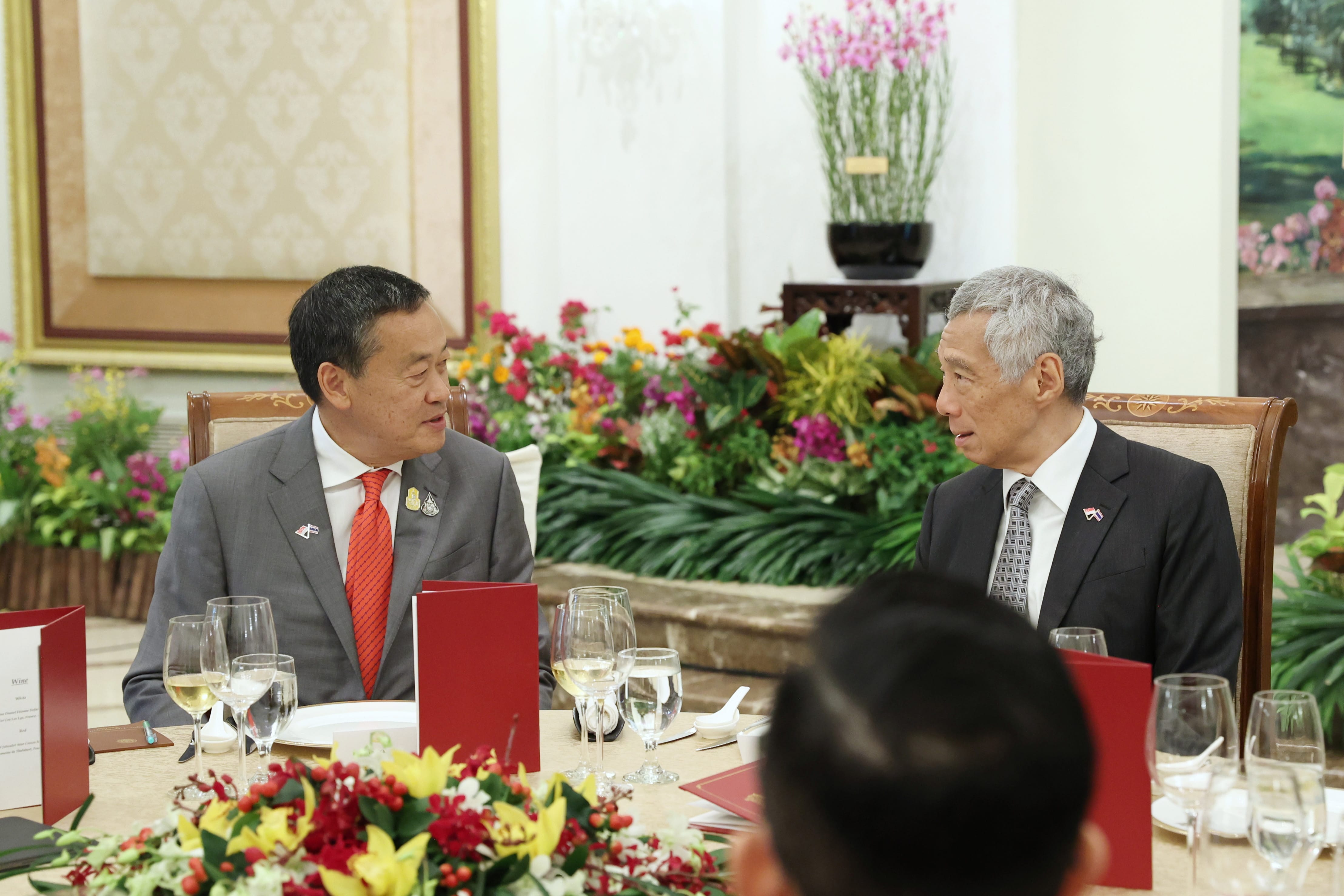 Lee Hsien Loong and another man in suits sit at a table during a formal dinner.