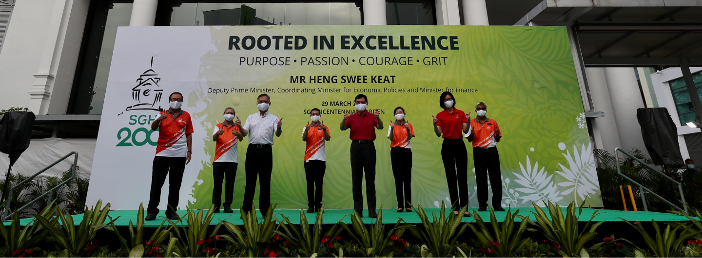 People in masks giving thumbs-up in front of "SGH 200" sign with Heng Swee Keat's name.