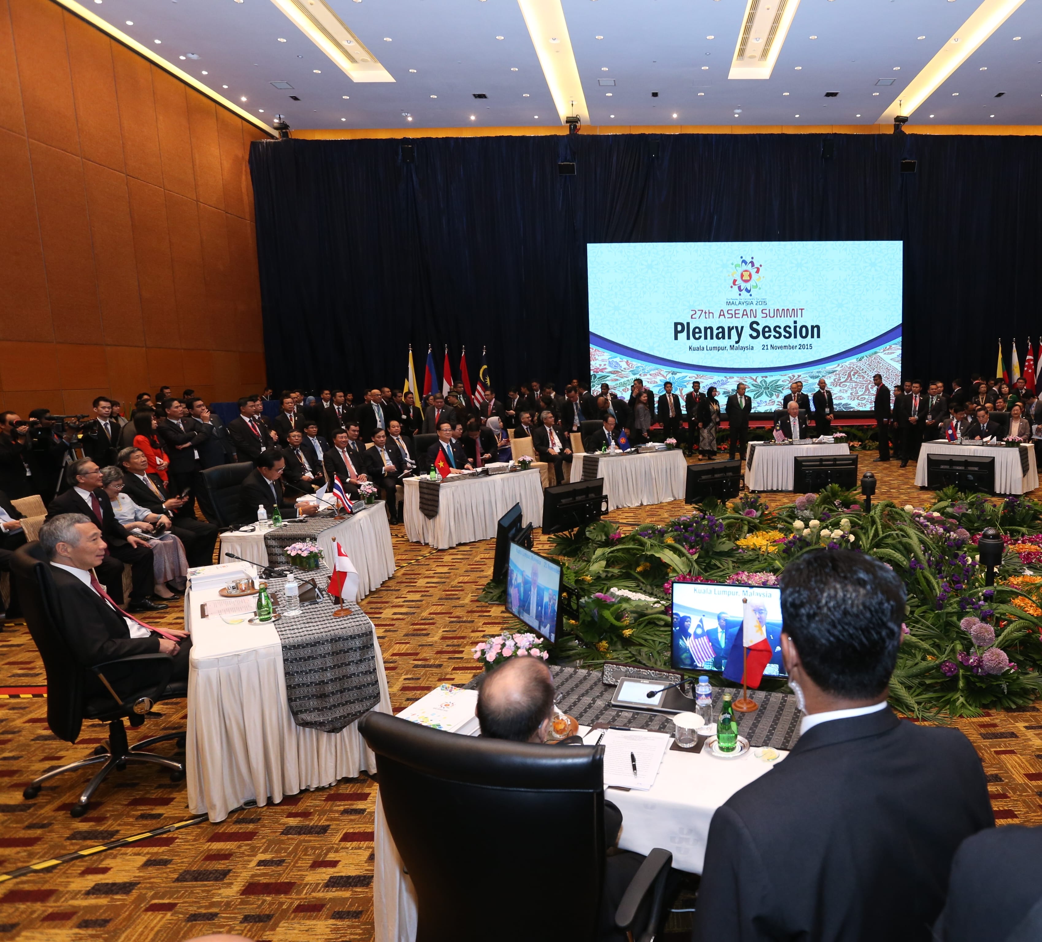 Large conference hall with delegates seated; screen reads "27th ASEAN Summit Plenary Session".
