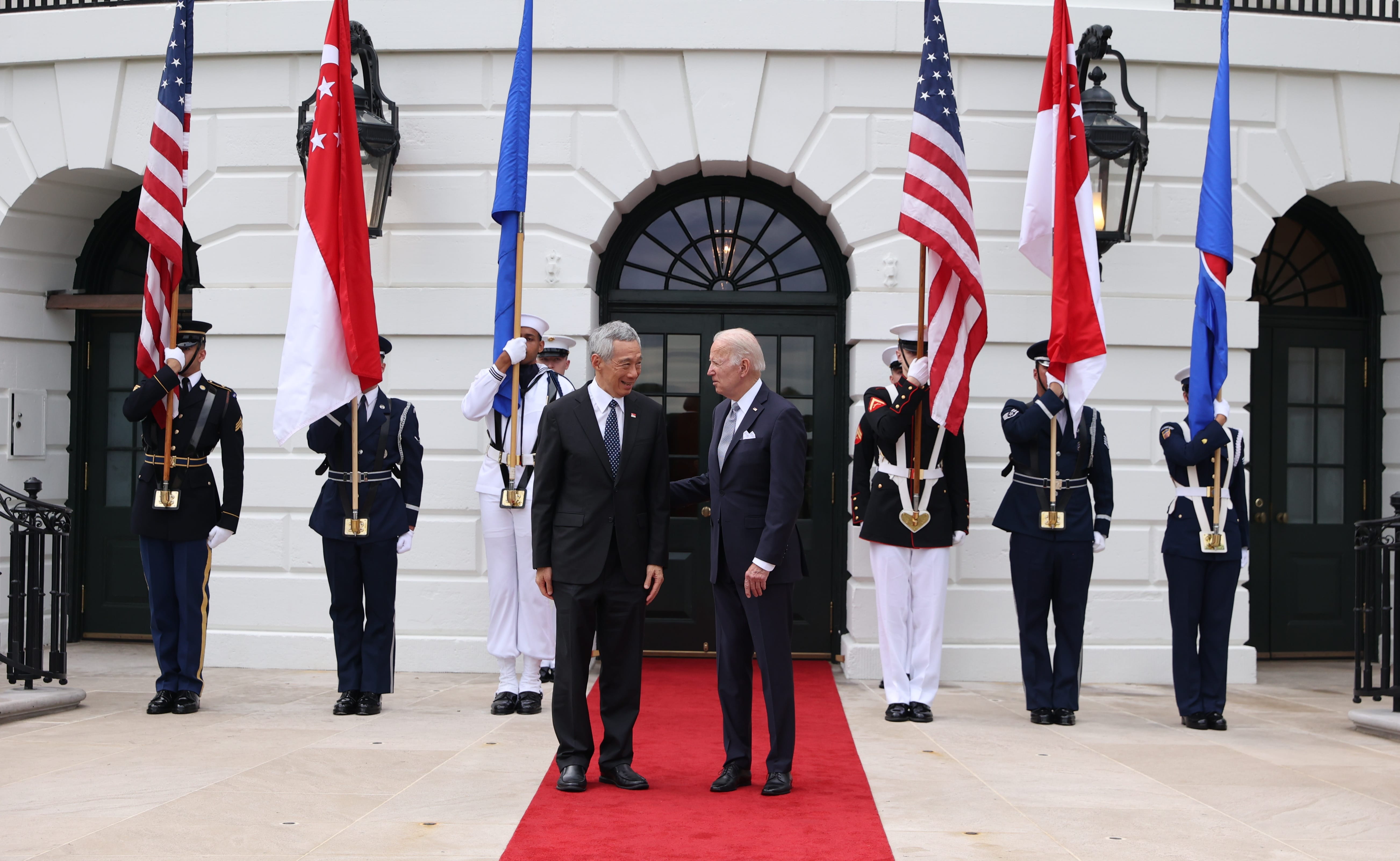 Joe Biden with Singapore's PM Lee Hsien Loong, flanked by color guard and US/Singapore flags.