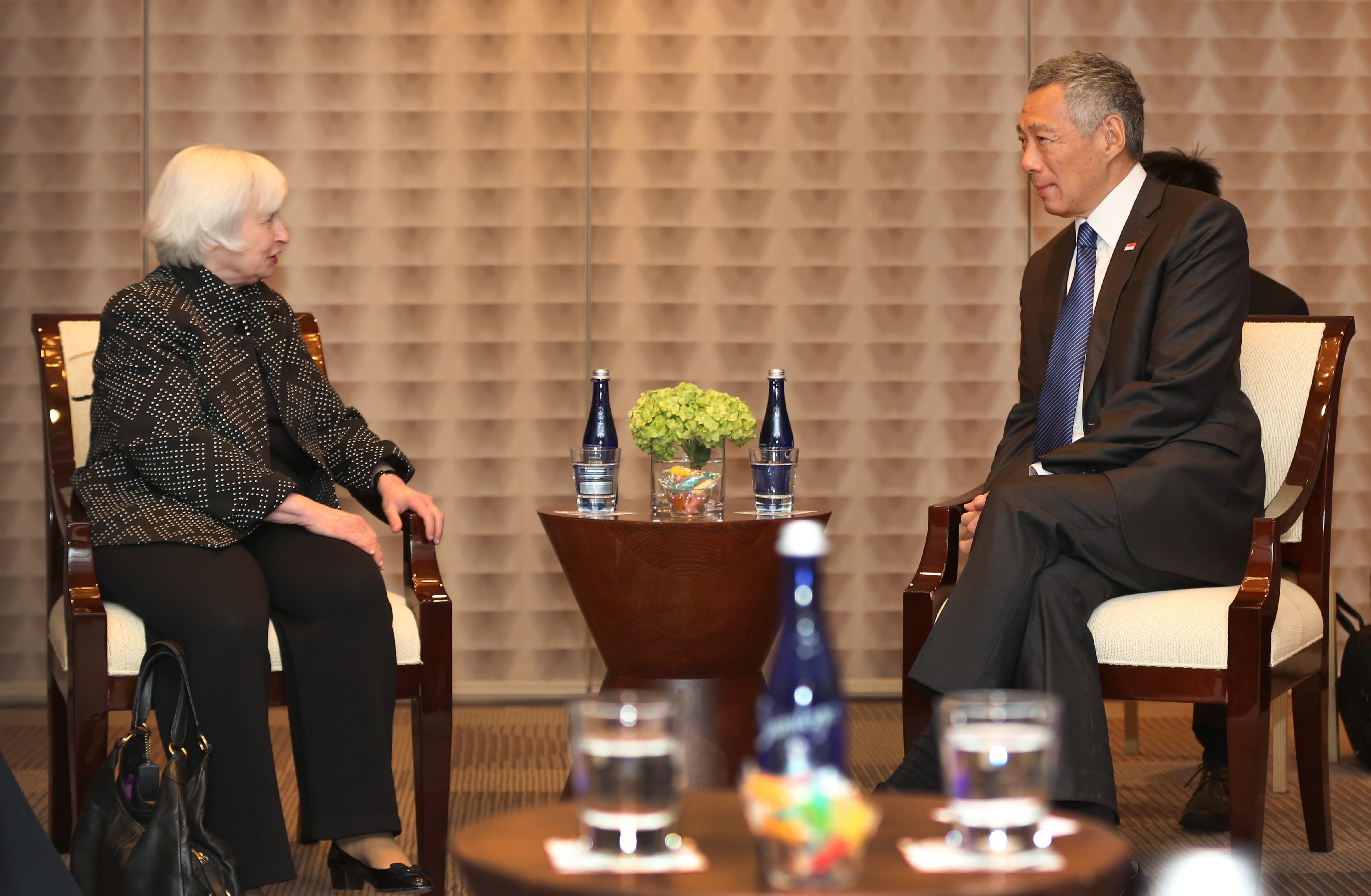 Janet Yellen and Lee Hsien Loong sitting in chairs, facing each other, bottles on table.
