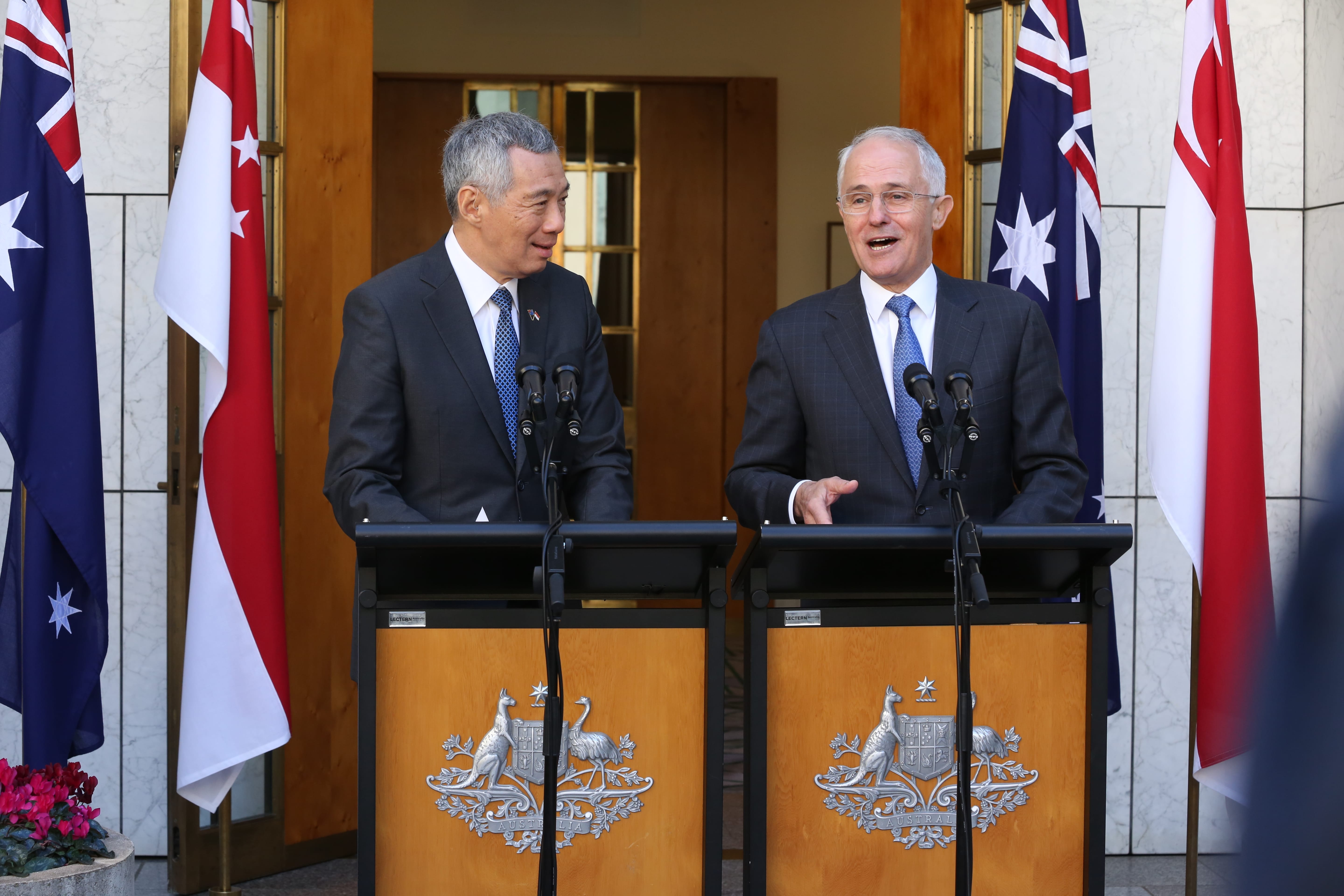 Lee Hsien Loong and Malcolm Turnbull at podiums with flags of Australia and Singapore.