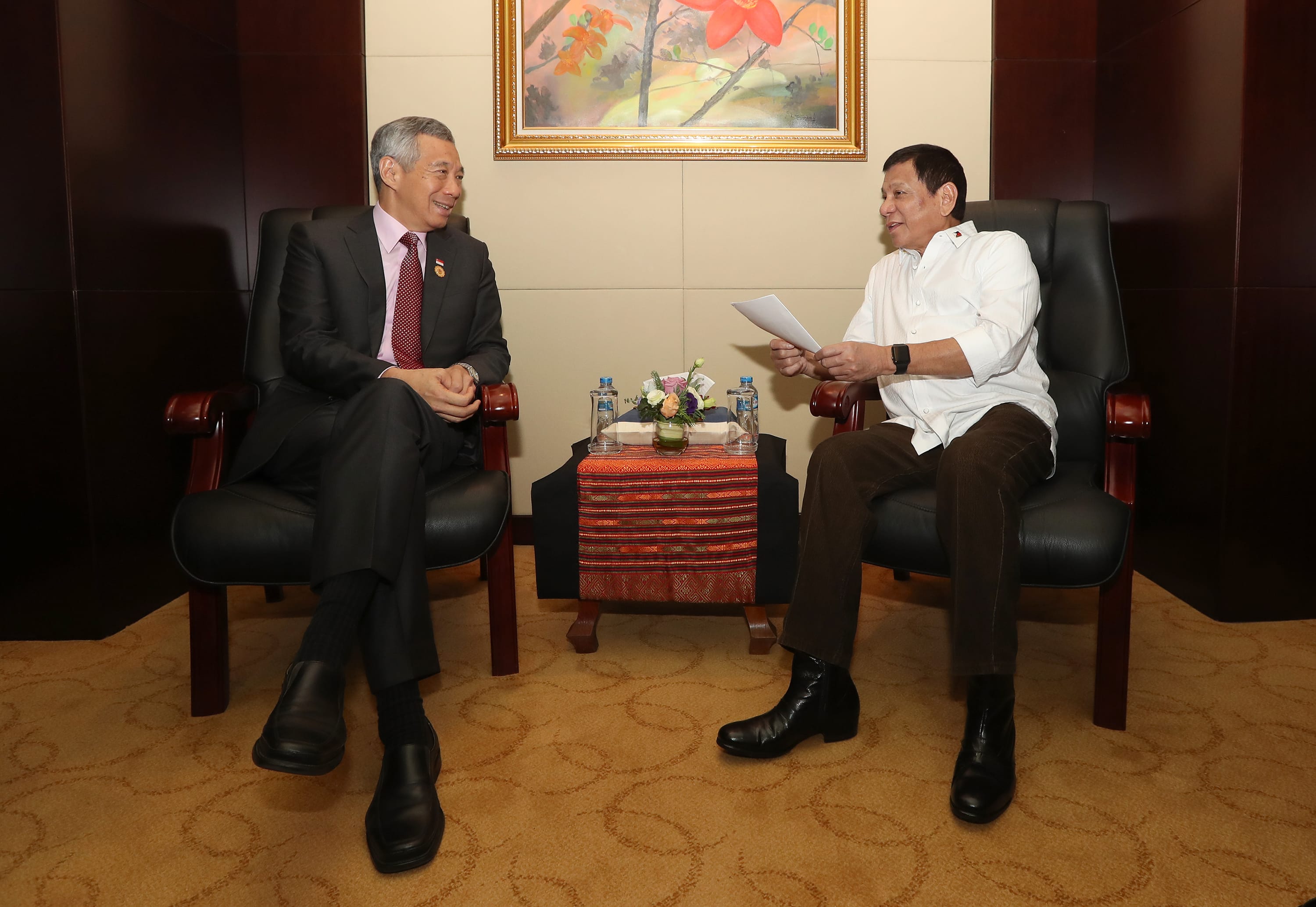 Lee Hsien Loong and Rodrigo Duterte in chairs, Duterte holds paper.