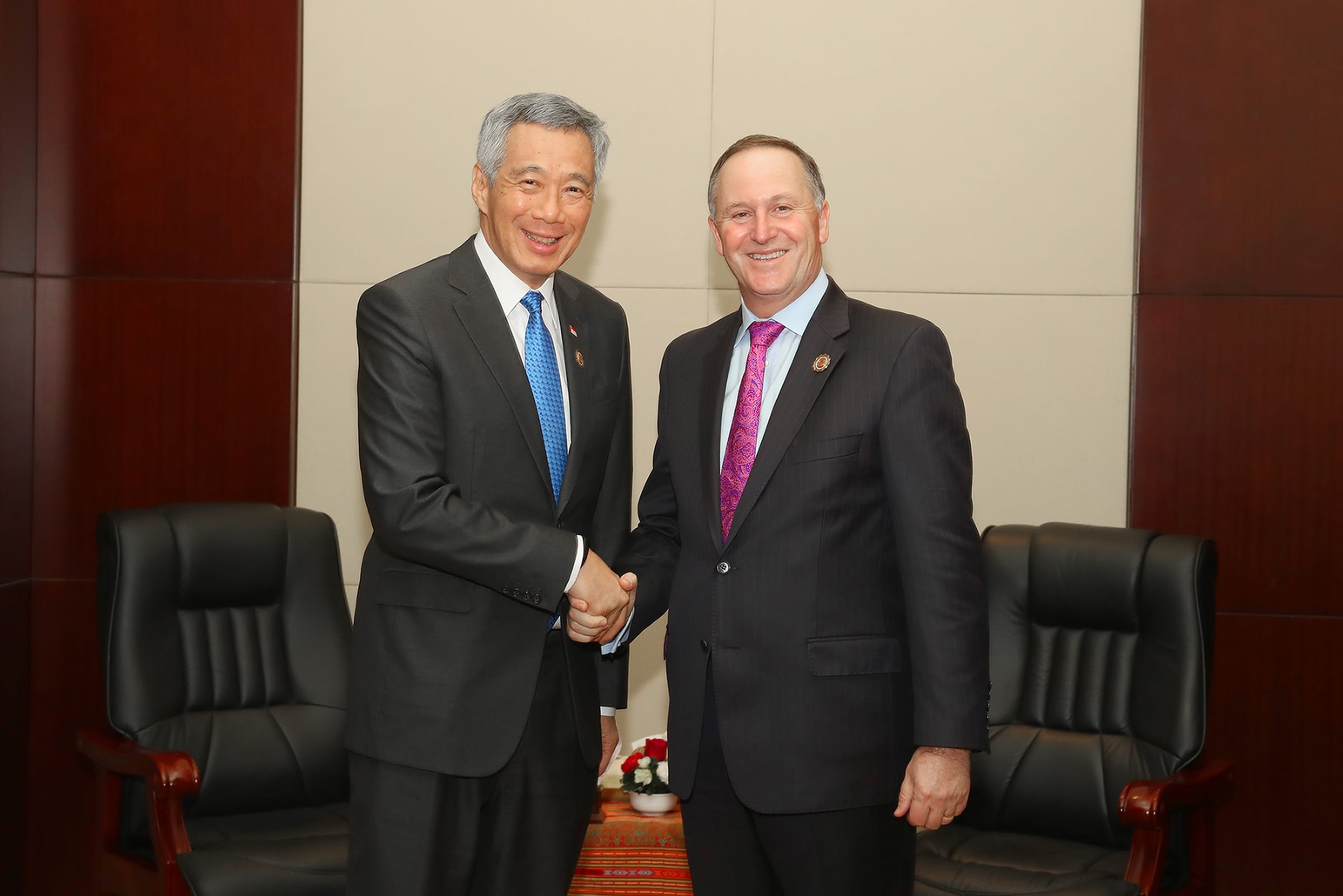 Lee Hsien Loong and John Key shake hands, both wearing dark suits and ties.
