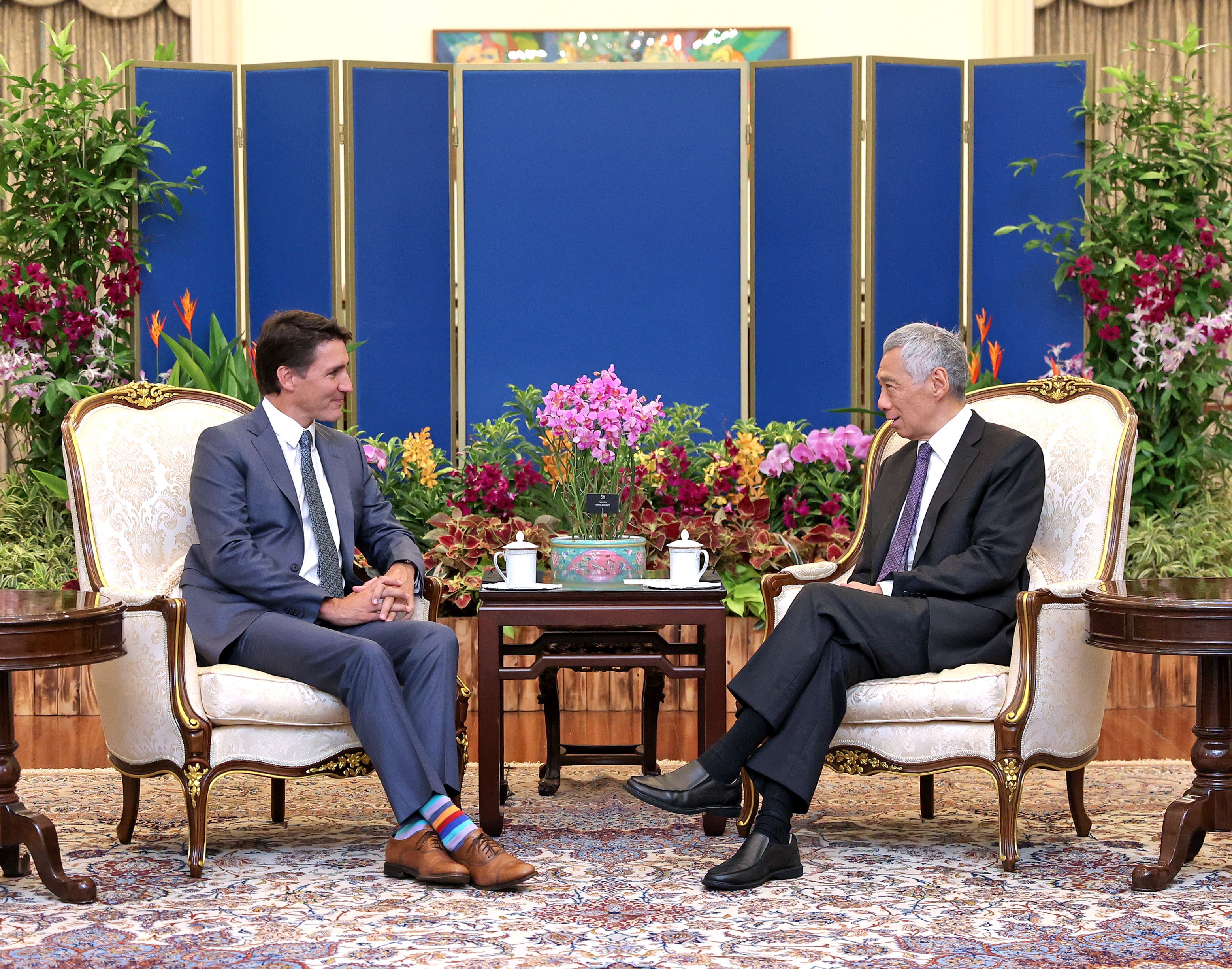 Justin Trudeau and Lee Hsien Loong in suits, seated in ornate chairs facing each other.