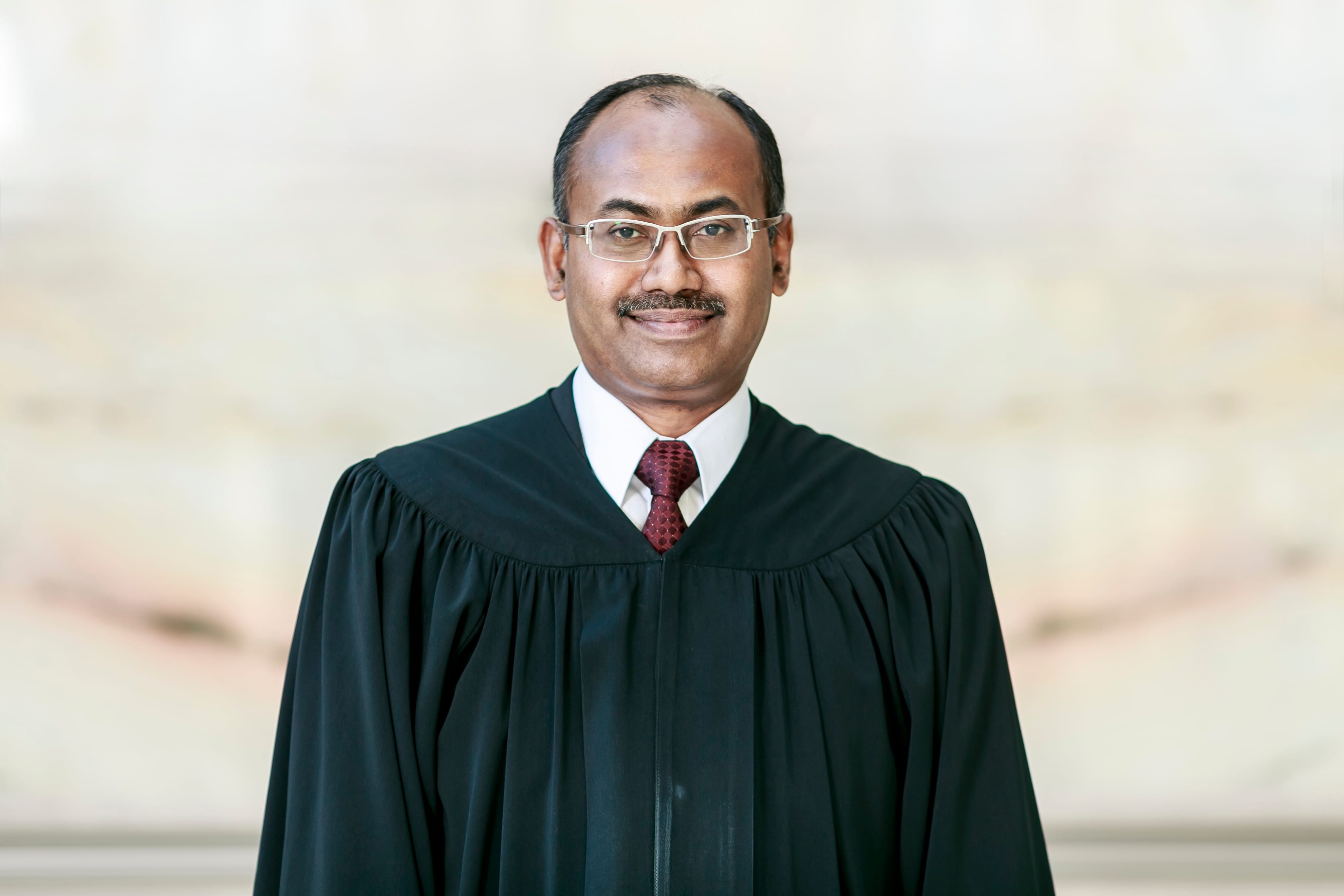 Portrait of a man wearing glasses and judicial robes.