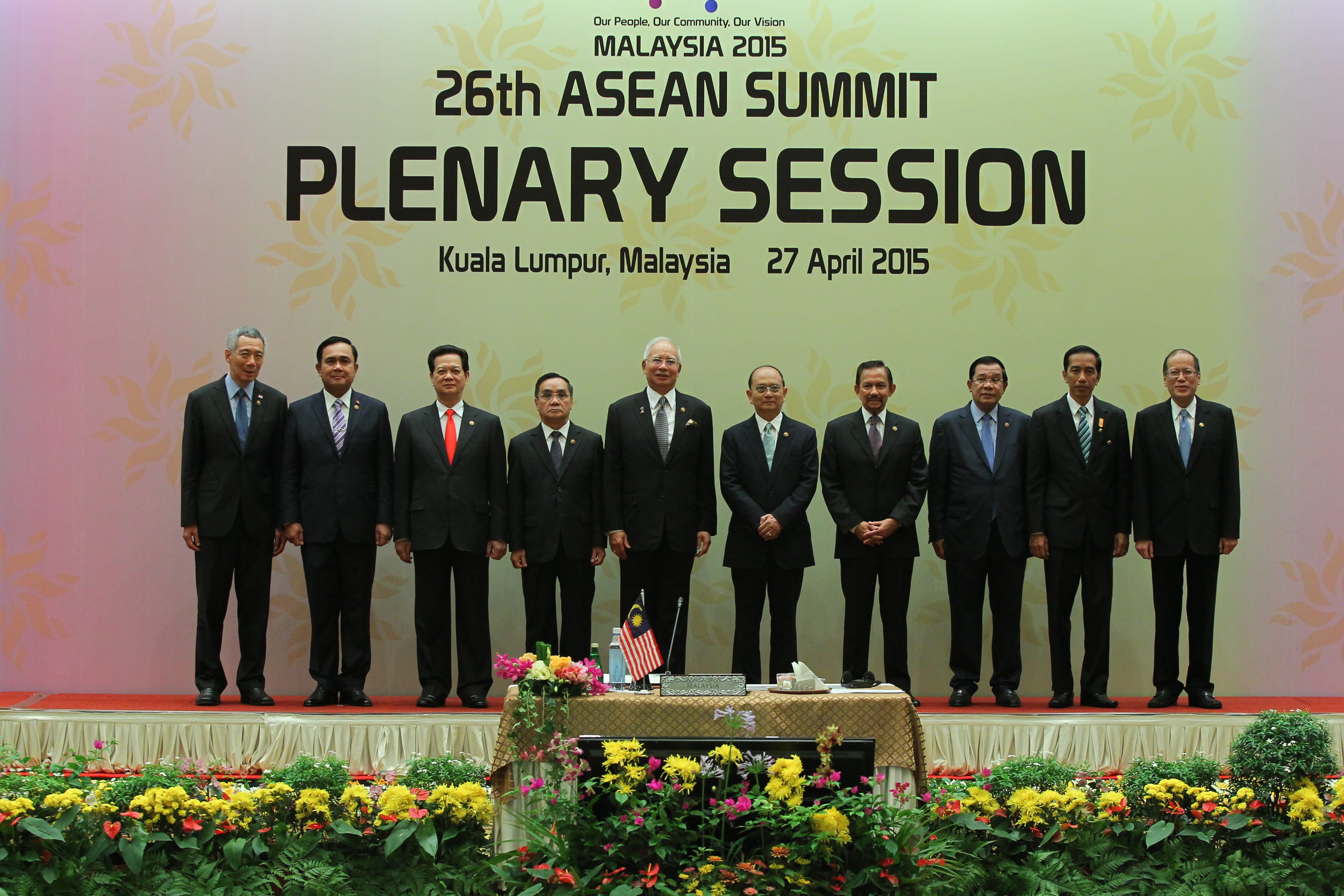 Group of 11 dignitaries stand on stage before '26th ASEAN Summit' backdrop.
