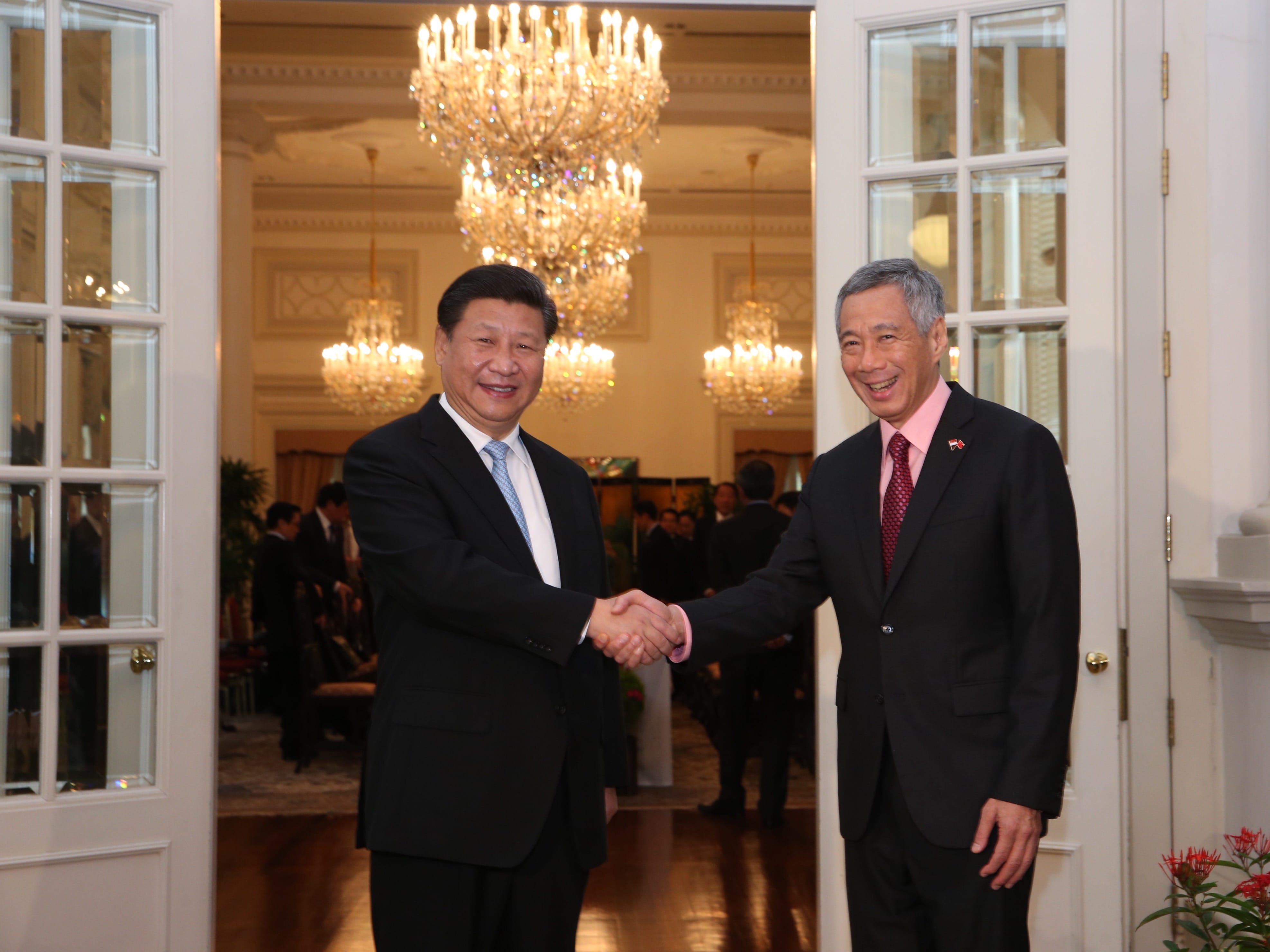 Xi Jinping and Lee Hsien Loong shake hands in an ornate room with chandeliers.