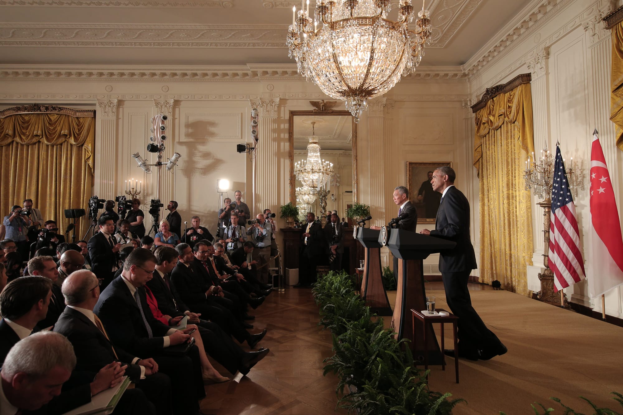 Obama at podium with Singapore's Prime Minister, ornate room, US and Singapore flags.