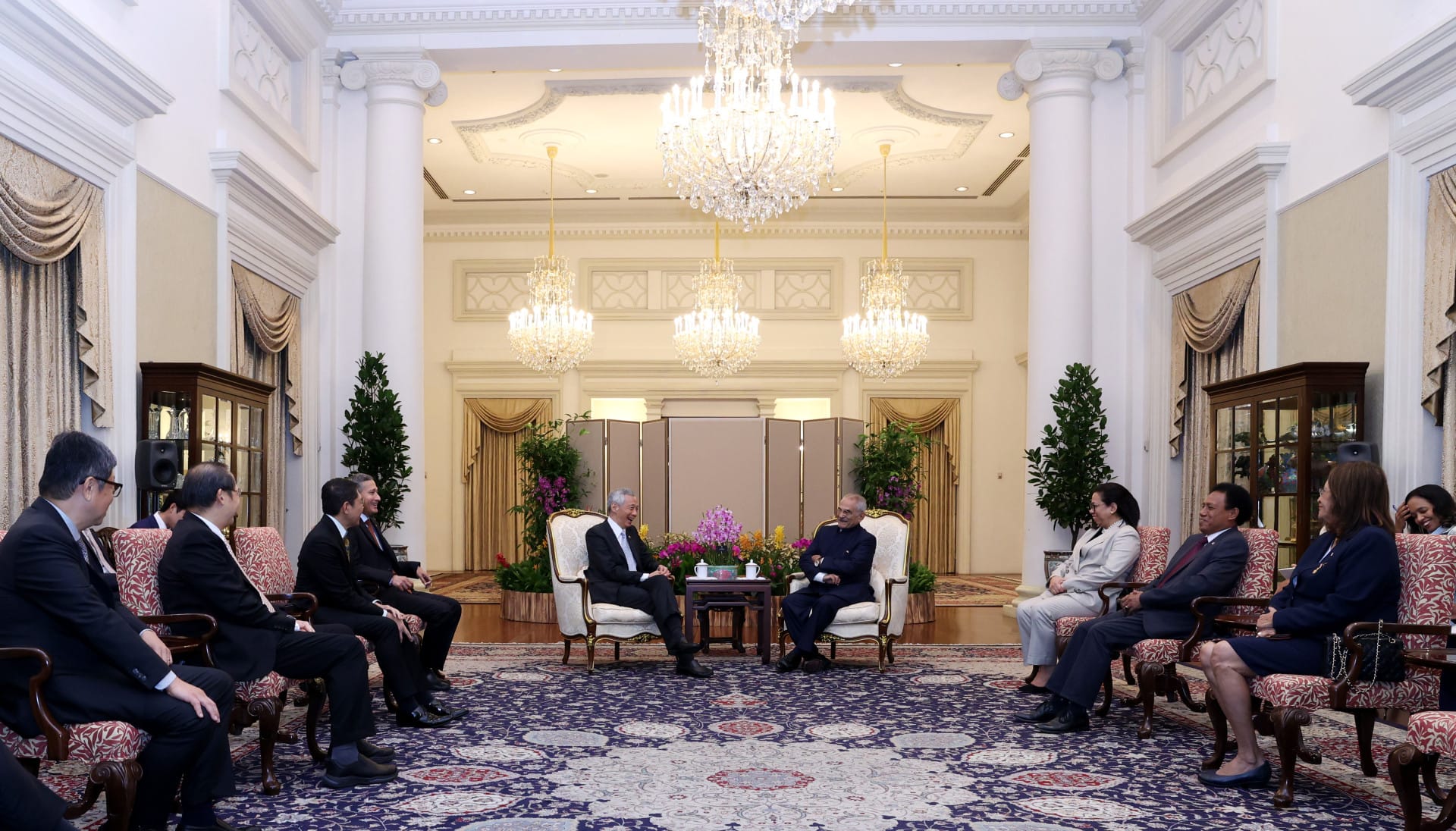 Lee Hsien Loong and Isaac Herzog meet with entourages in a grand room.