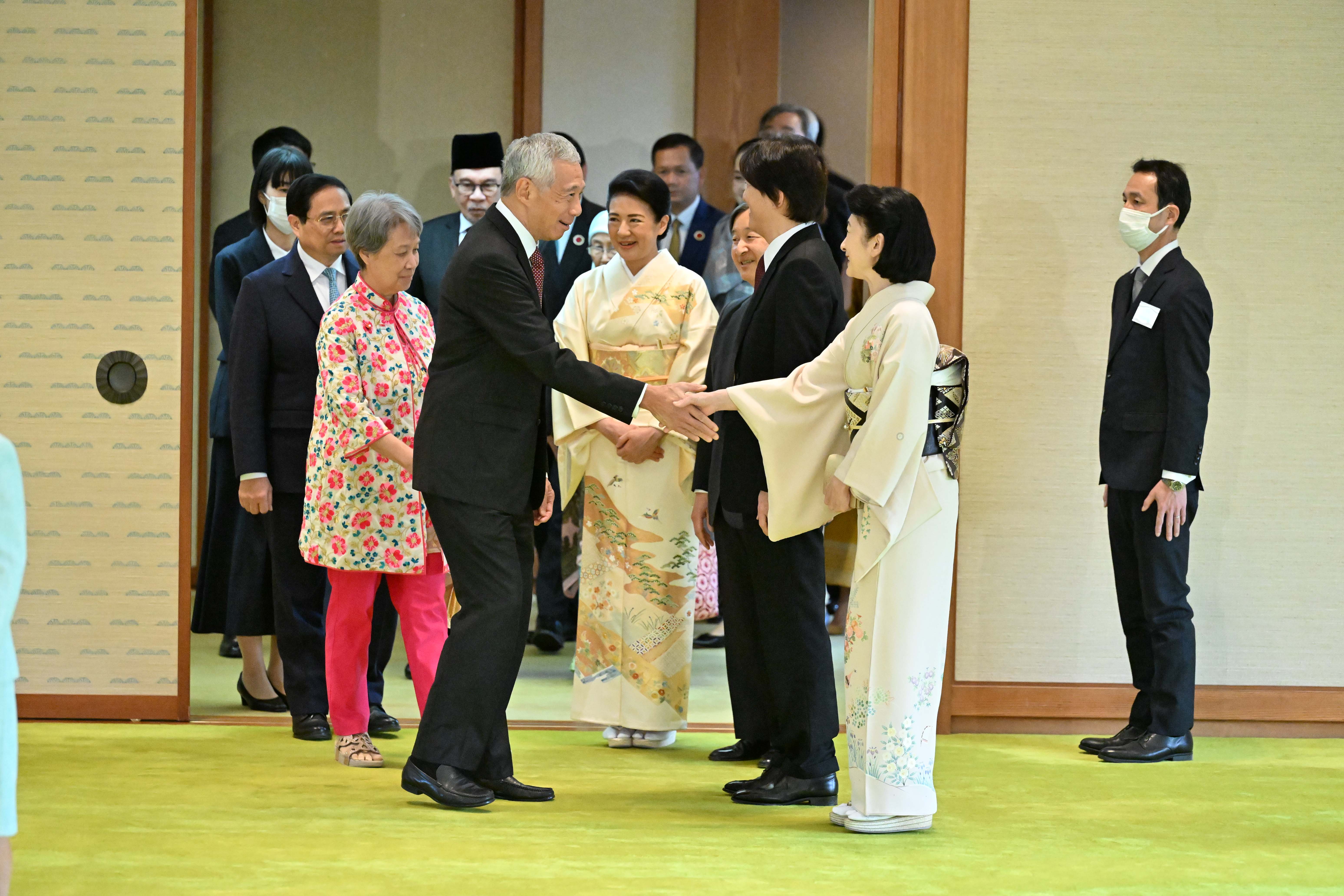 Lee Hsien Loong shaking hands with woman in kimono, among others in suits and Japanese attire.