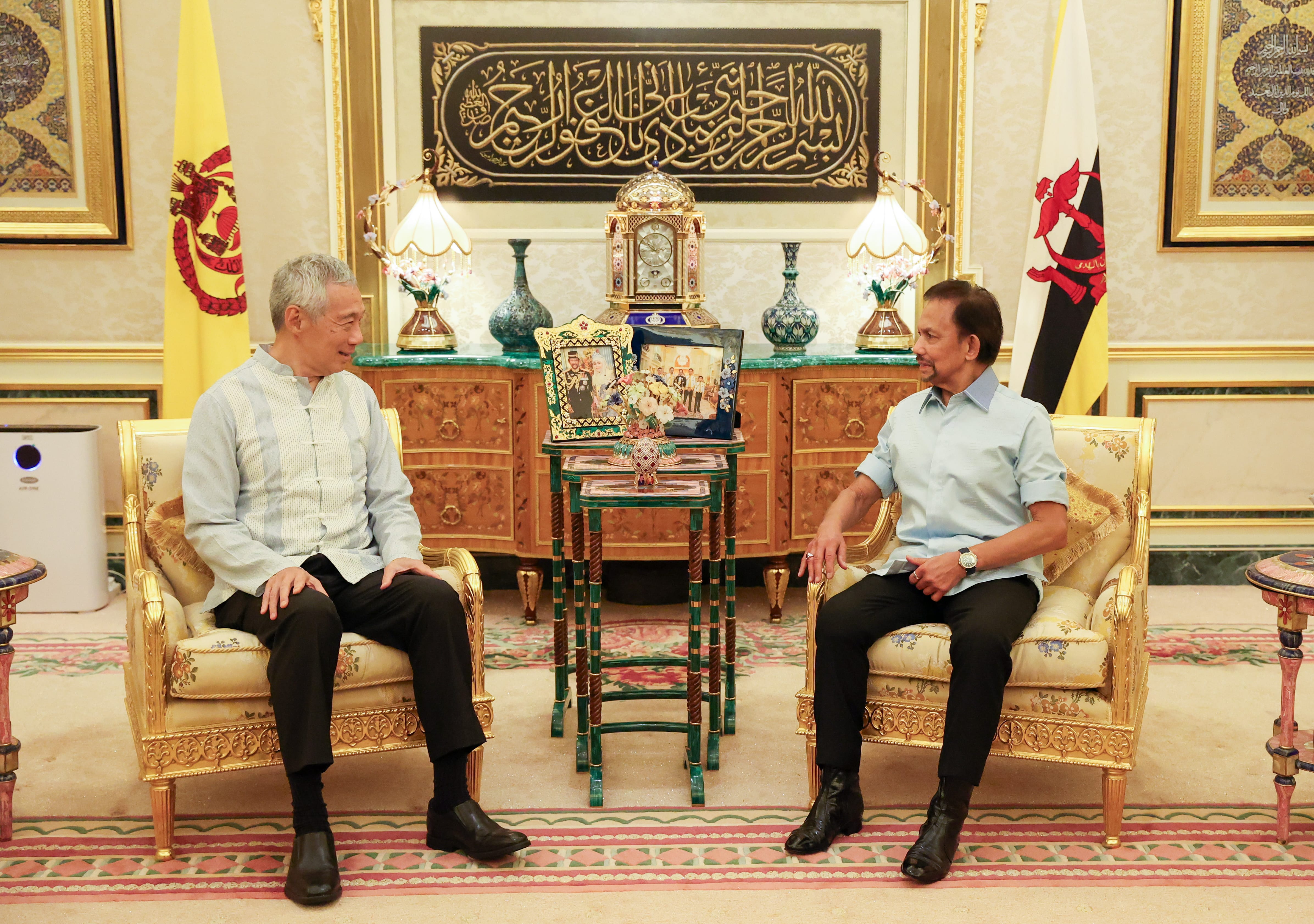 Lee Hsien Loong and Hassanal Bolkiah seated, facing each other in ornate chairs with Brunei flags displayed.