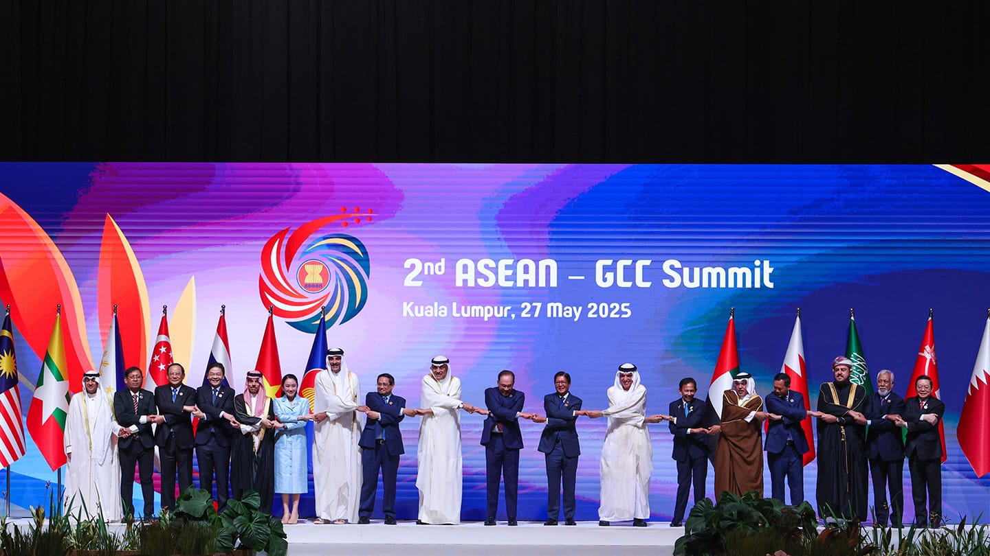ASEAN-GCC Summit: Leaders in suits/robes hold hands before flags, with "2nd ASEAN-GCC Summit" on a bright screen behind.