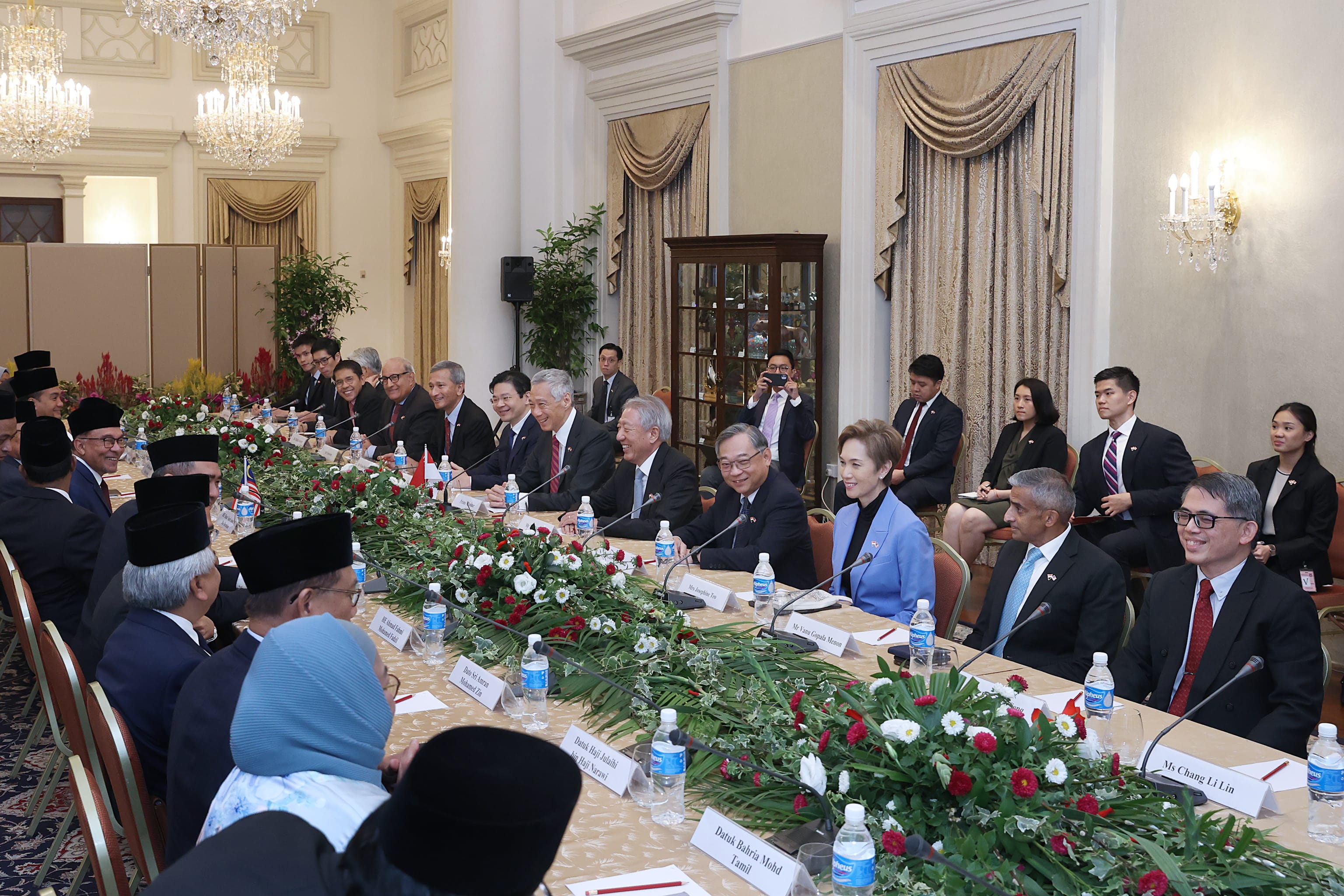 People seated at long table with flower garland centerpiece and nameplates.