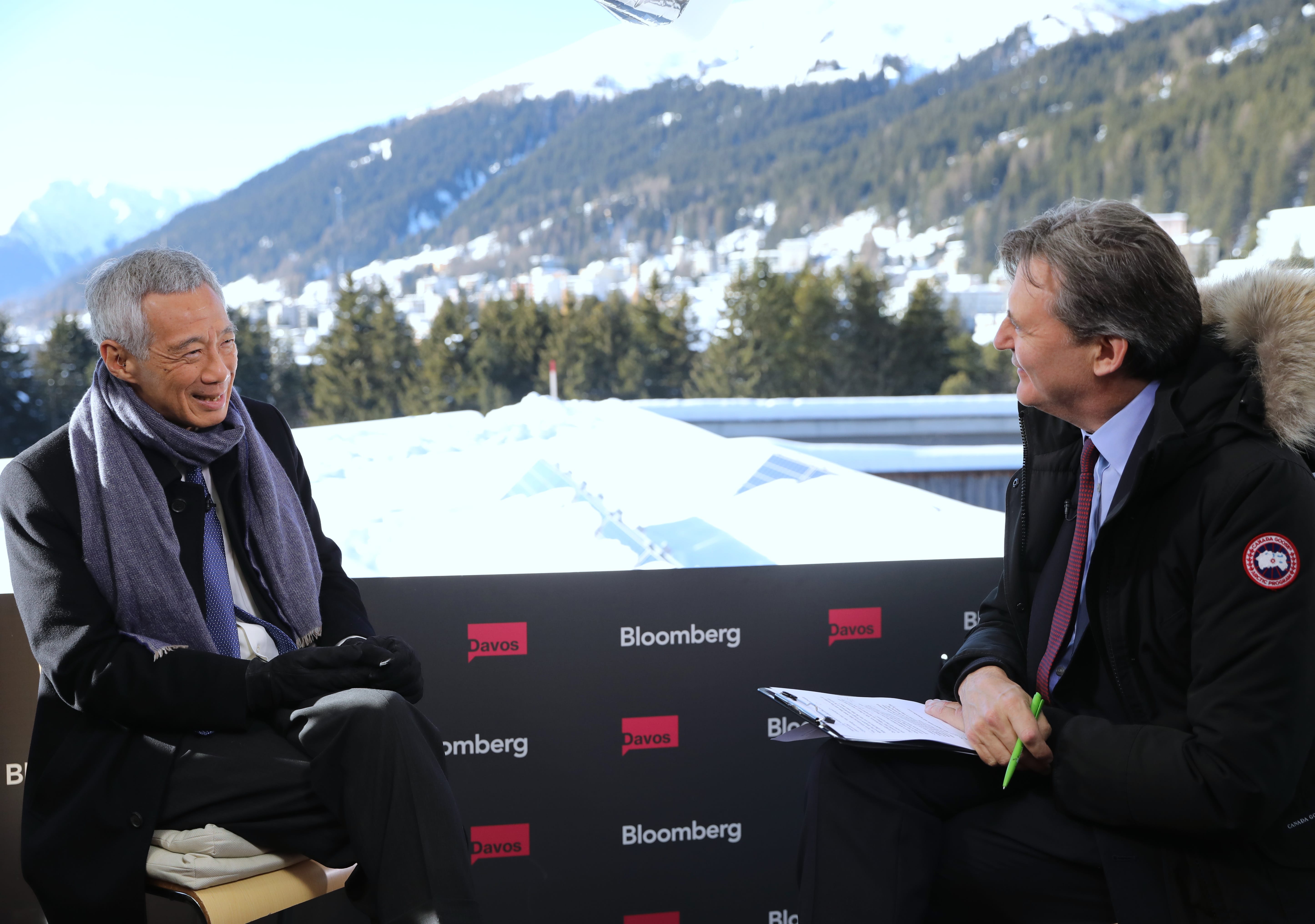 Lee Hsien Loong interviews with Bloomberg at Davos, snow-covered mountains in background.