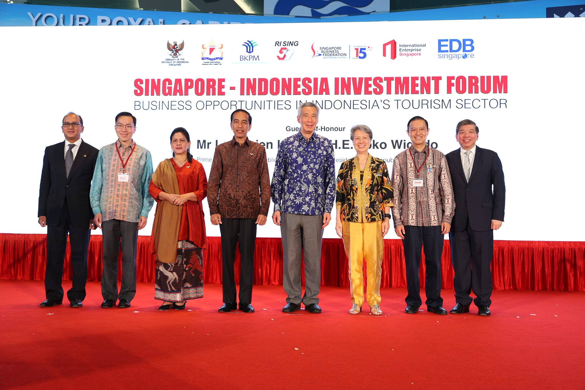 Group of people stand on stage at Singapore-Indonesia Investment Forum in front of event logos and text.