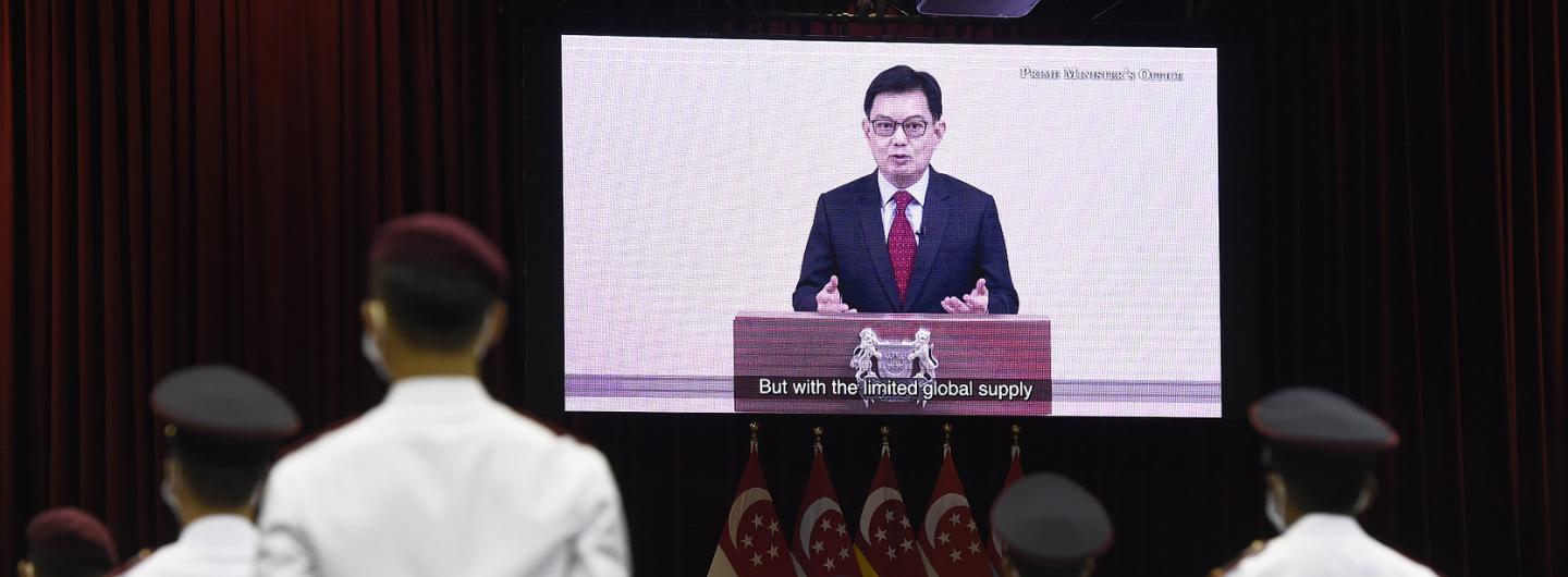 Singapore military personnel view PM Lee Hsien Loong on screen, addressing "limited global supply."