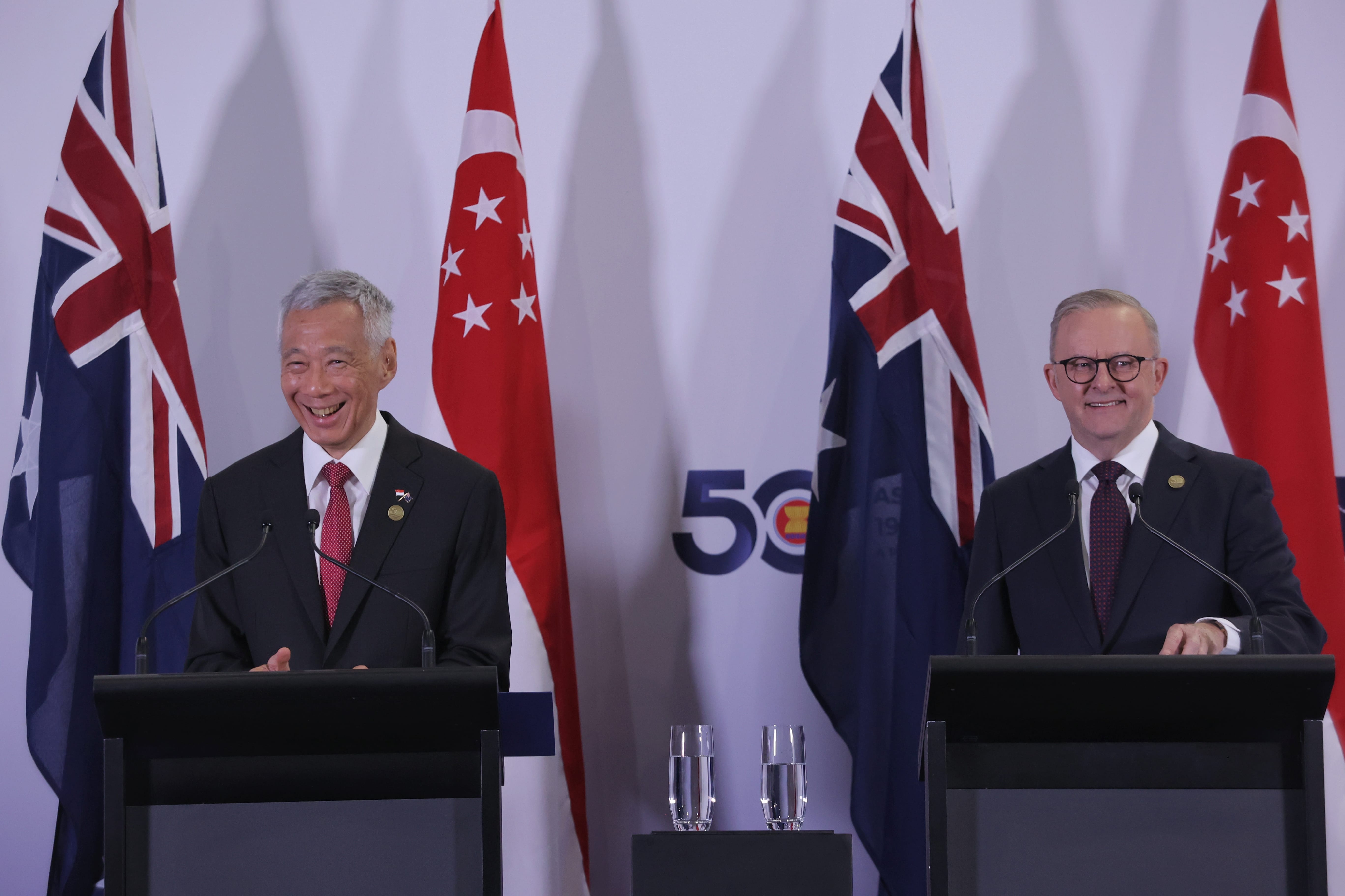 Lee Hsien Loong and Anthony Albanese at lecterns with Australian and Singaporean flags.