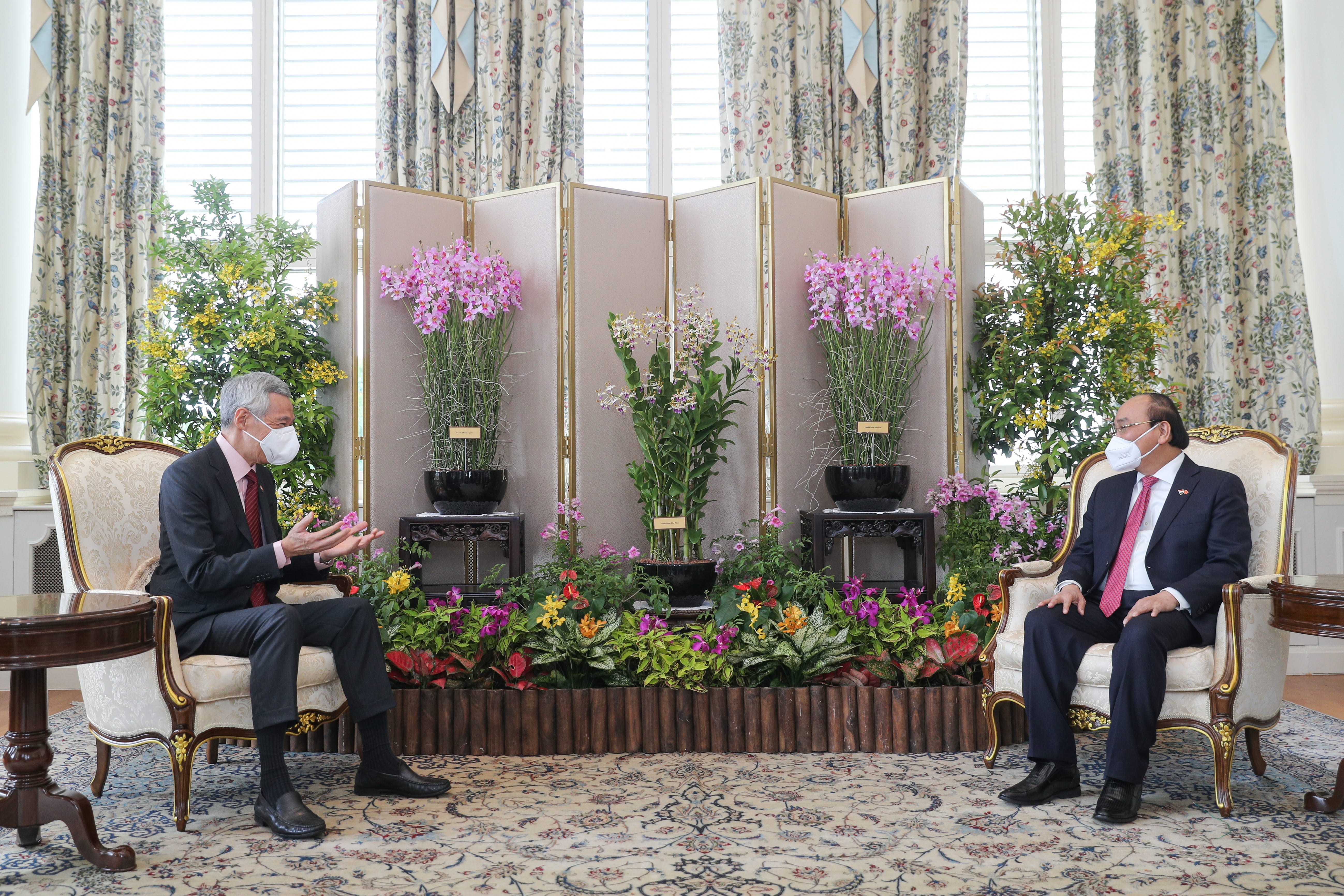 Lee Hsien Loong and Nguyễn Xuân Phúc seated across from each other indoors, both wearing masks and suits.
