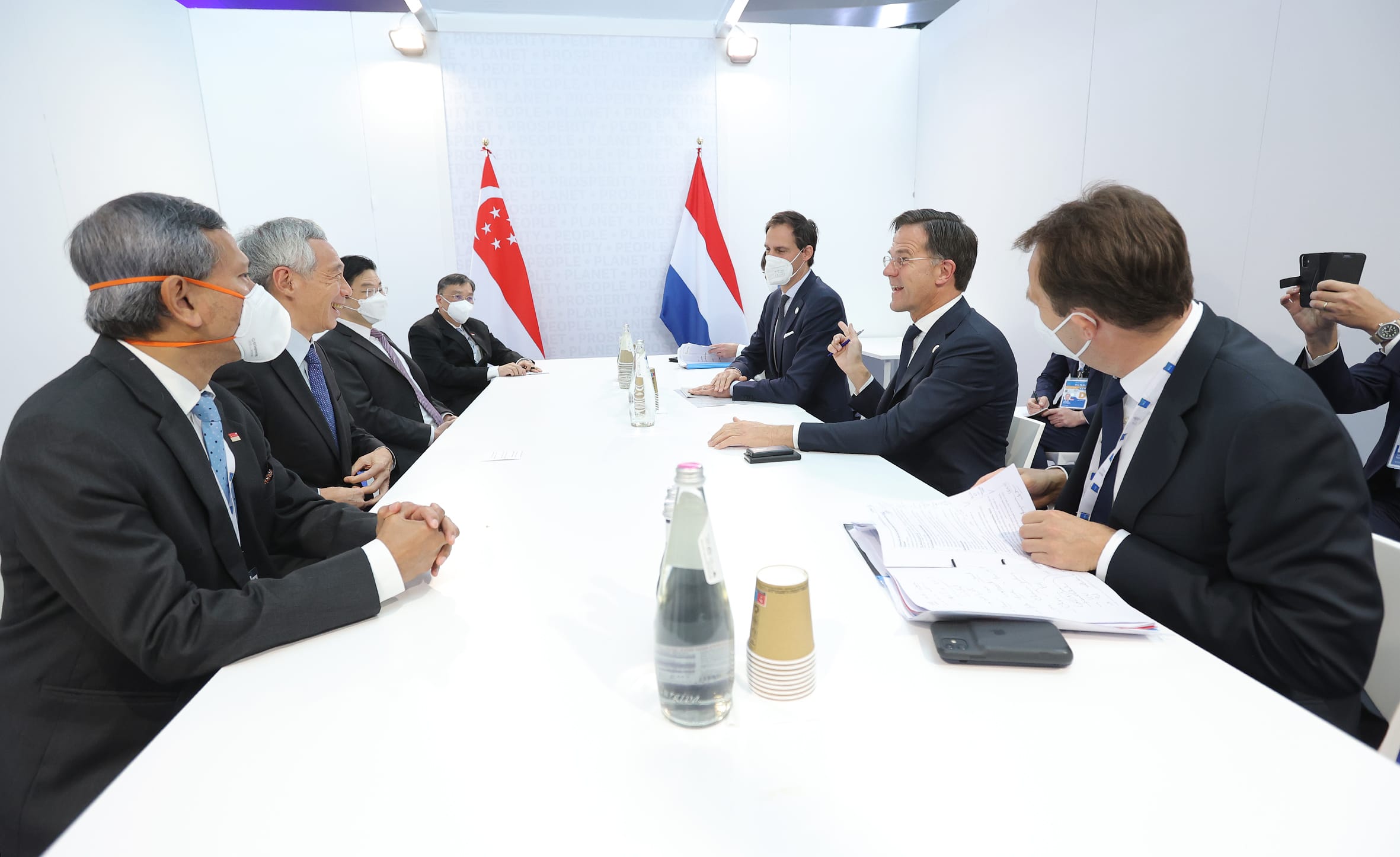 Delegation meeting at table, with Singaporean & Dutch flags displayed in the background.