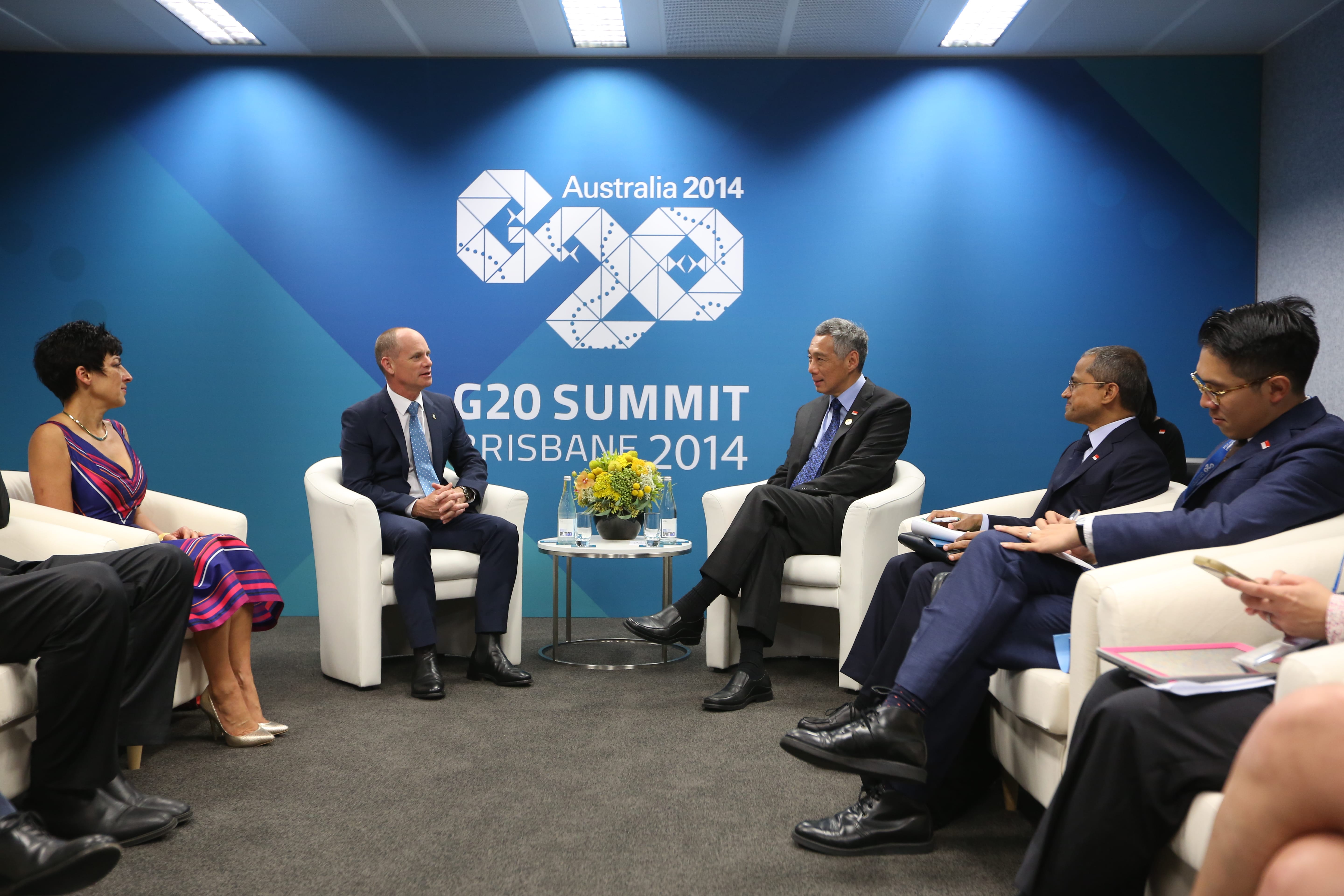 People seated at a G20 Summit Brisbane 2014 event with logo on a blue backdrop.