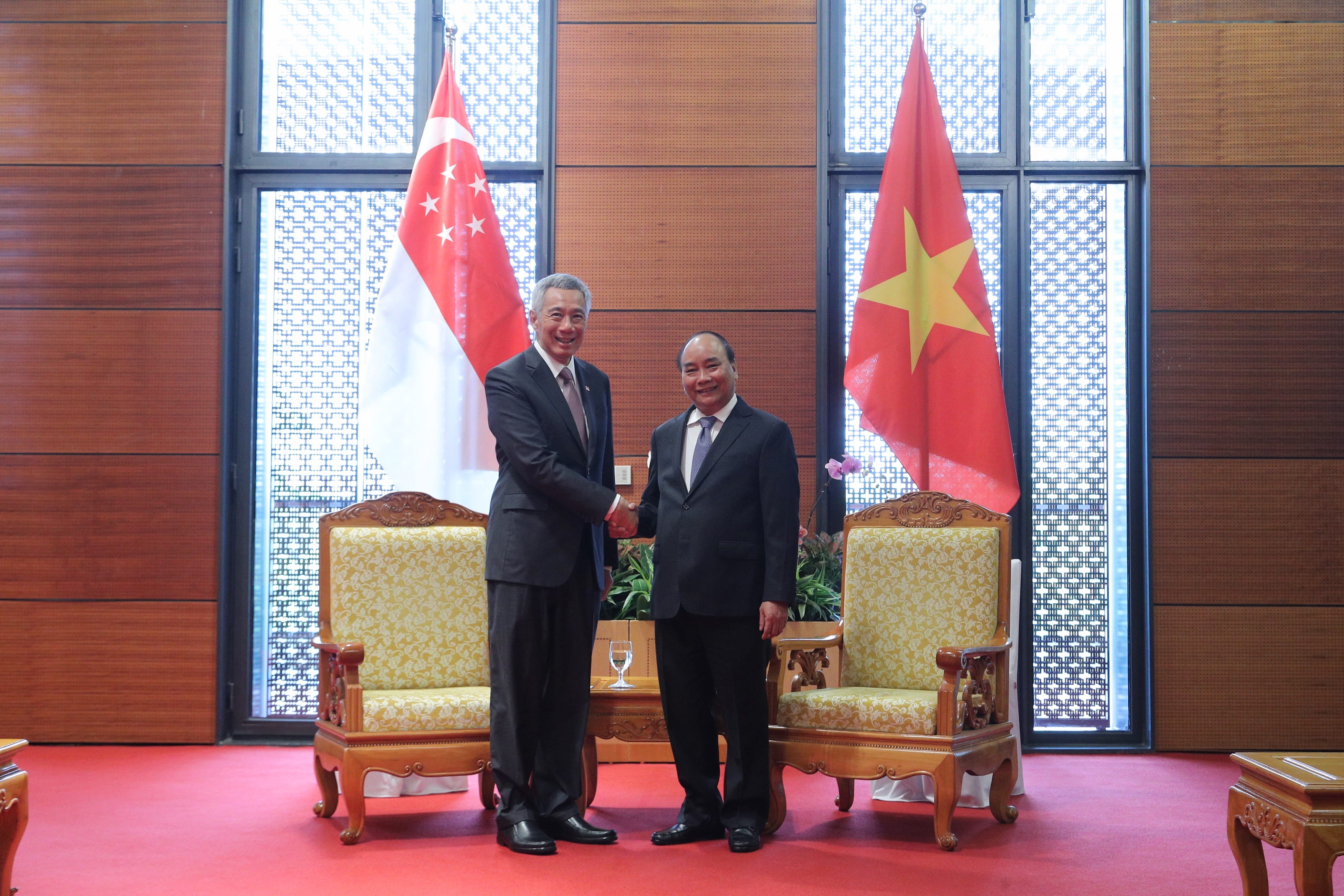 Lee Hsien Loong and Nguyễn Xuân Phúc shake hands, with Singapore and Vietnam flags behind them.