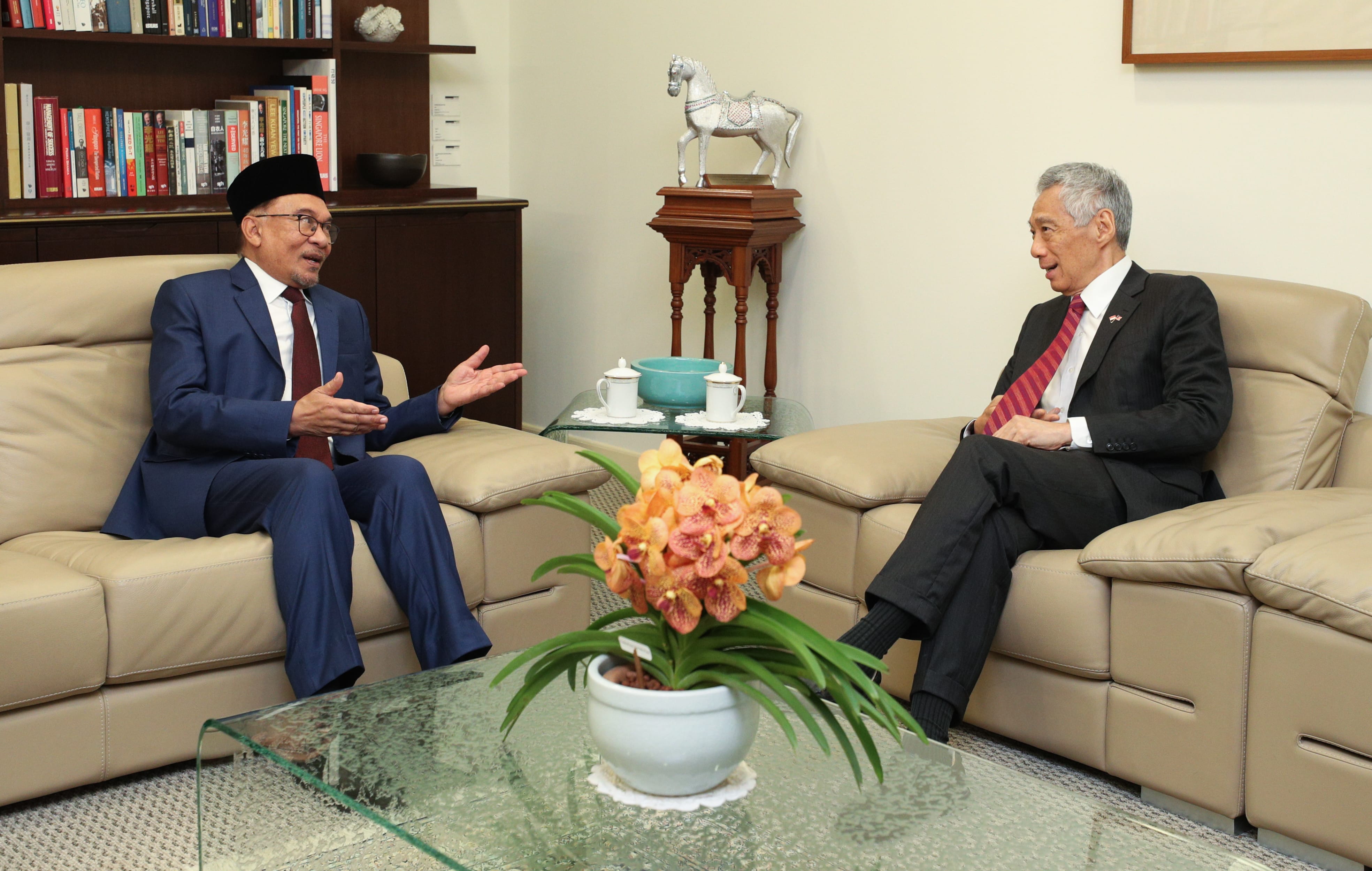 Lee Hsien Loong and Anwar Ibrahim in suits sitting on a couch across from each other.