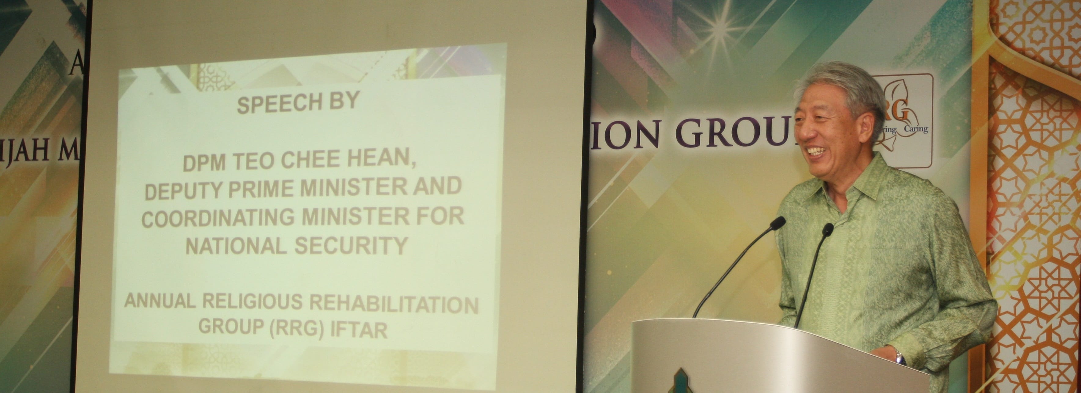 DPM Teo Chee Hean at a podium with the Annual Religious Rehabilitation Group (RRG) Iftar details on a screen.
