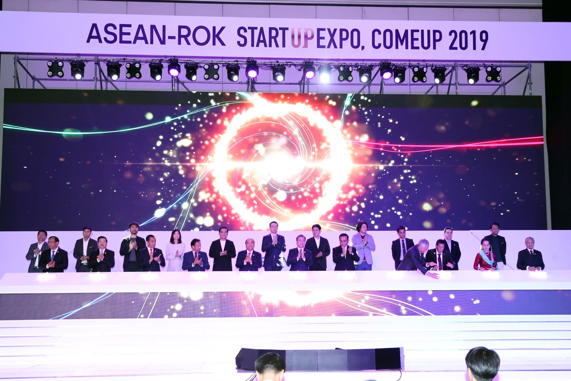 People at ASEAN-ROK Startup Expo, COMEUP 2019. Digital backdrop with concentric circles.