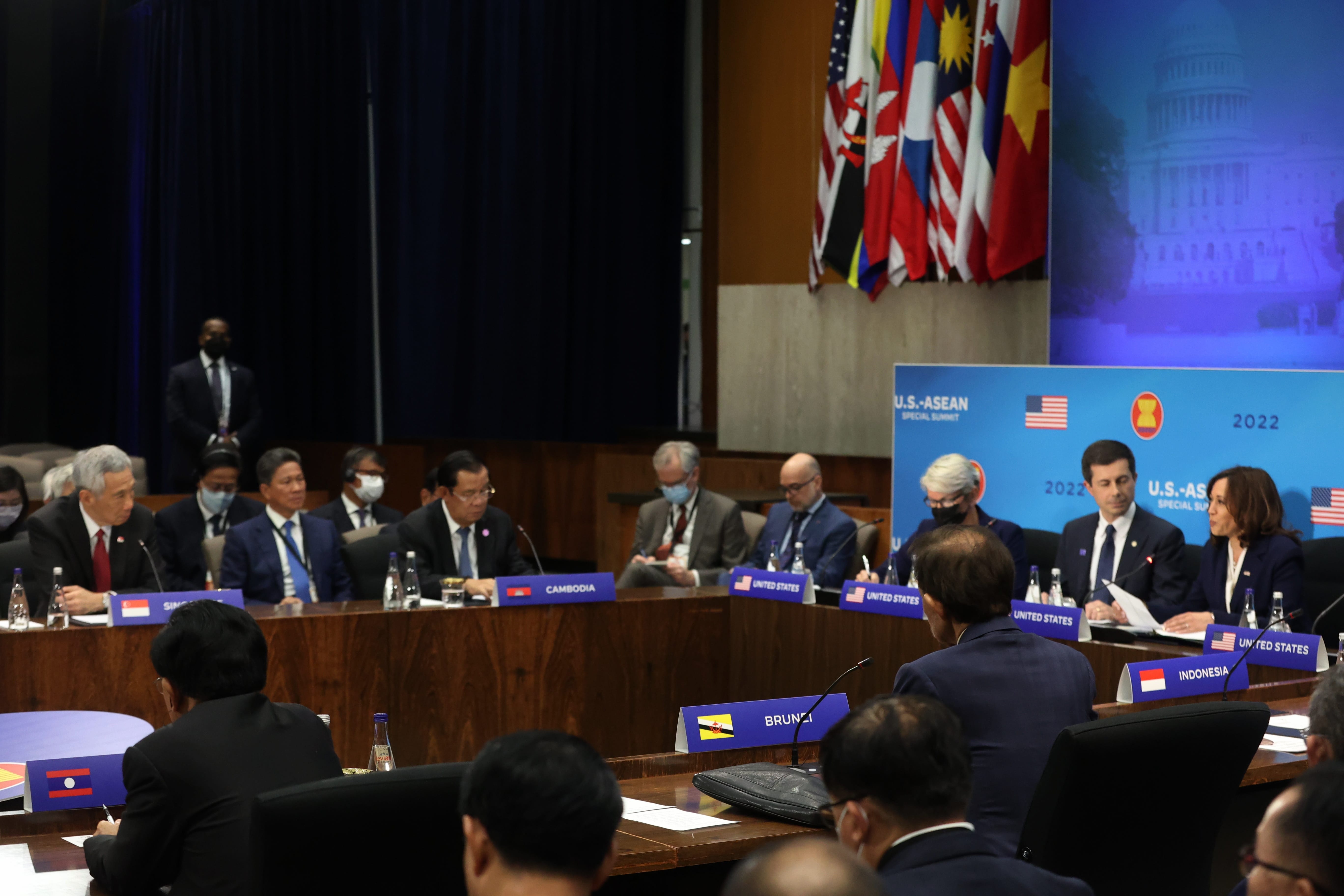 U.S.-ASEAN summit, attendees at tables with country nameplates, flags displayed, Harris and Buttigieg.