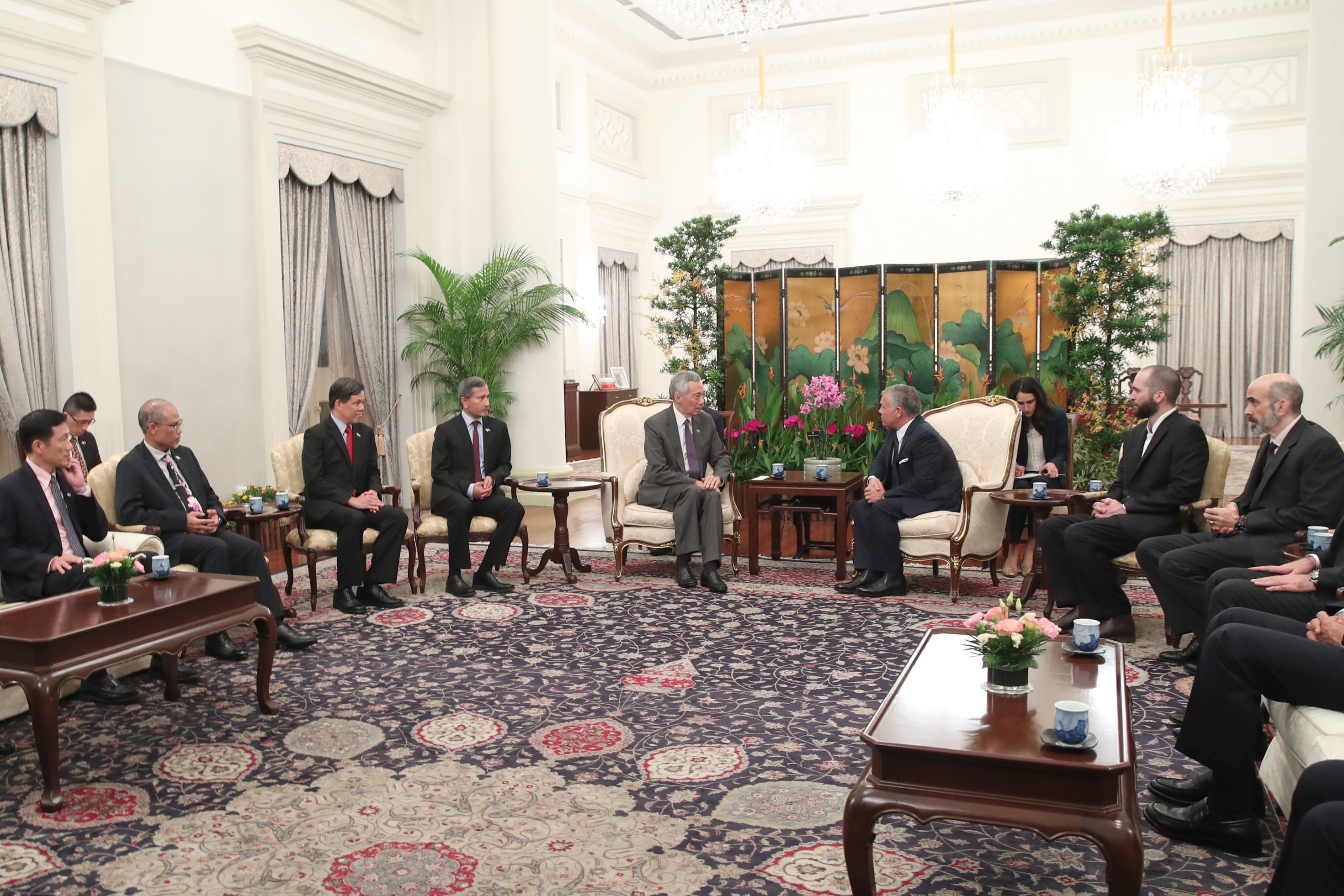Men in suits seated in chairs on an ornate rug, ornate room. Lee Hsien Loong is present.